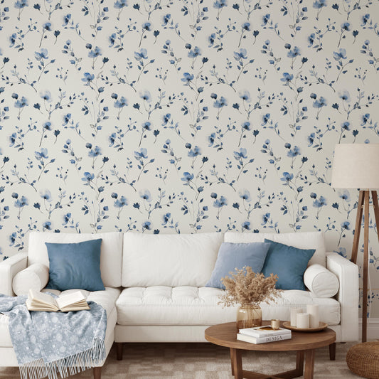 a living room with a white sofa, a coffee table, and a lamp. The wall behind the sofa has a floral wallpaper pattern in shades of blue and white.
