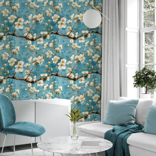 a living room with a large wallpapered wall adorned with a floral design in shades of blue and white. The room is furnished with a white sofa, a blue armchair, and a round marble coffee table. A potted plant is placed on the floor, and a vase with flowers is also present on the coffee table.