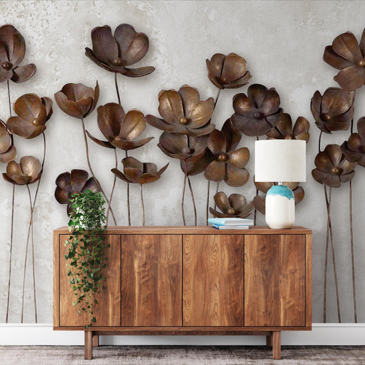 a wooden cabinet with a lamp on top, set against a wall adorned with large, intricately designed metal flower sculptures.