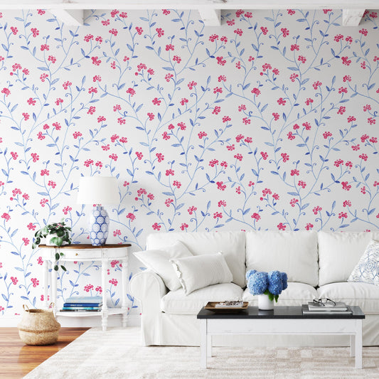 a cozy living room with a white sofa, a coffee table, and a lamp. The walls are covered in a floral wallpaper with red and blue flowers, creating a vibrant and cheerful atmosphere.