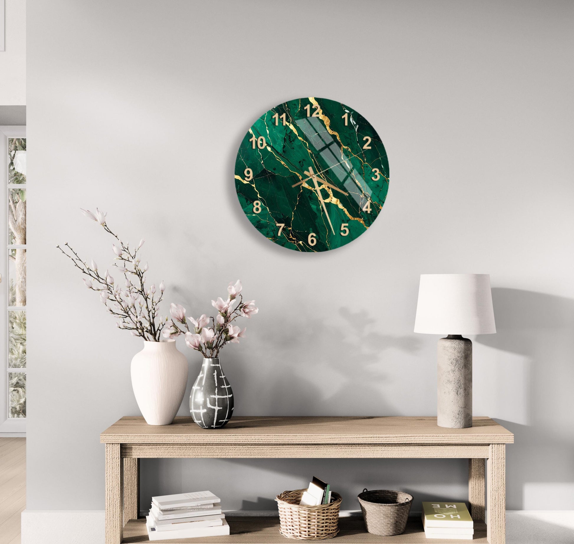 a modern living room with a large green marble-like clock hanging on the wall above a wooden table. The table has a lamp, a vase with flowers, and some books on it. The overall decor has a minimalist and elegant style.