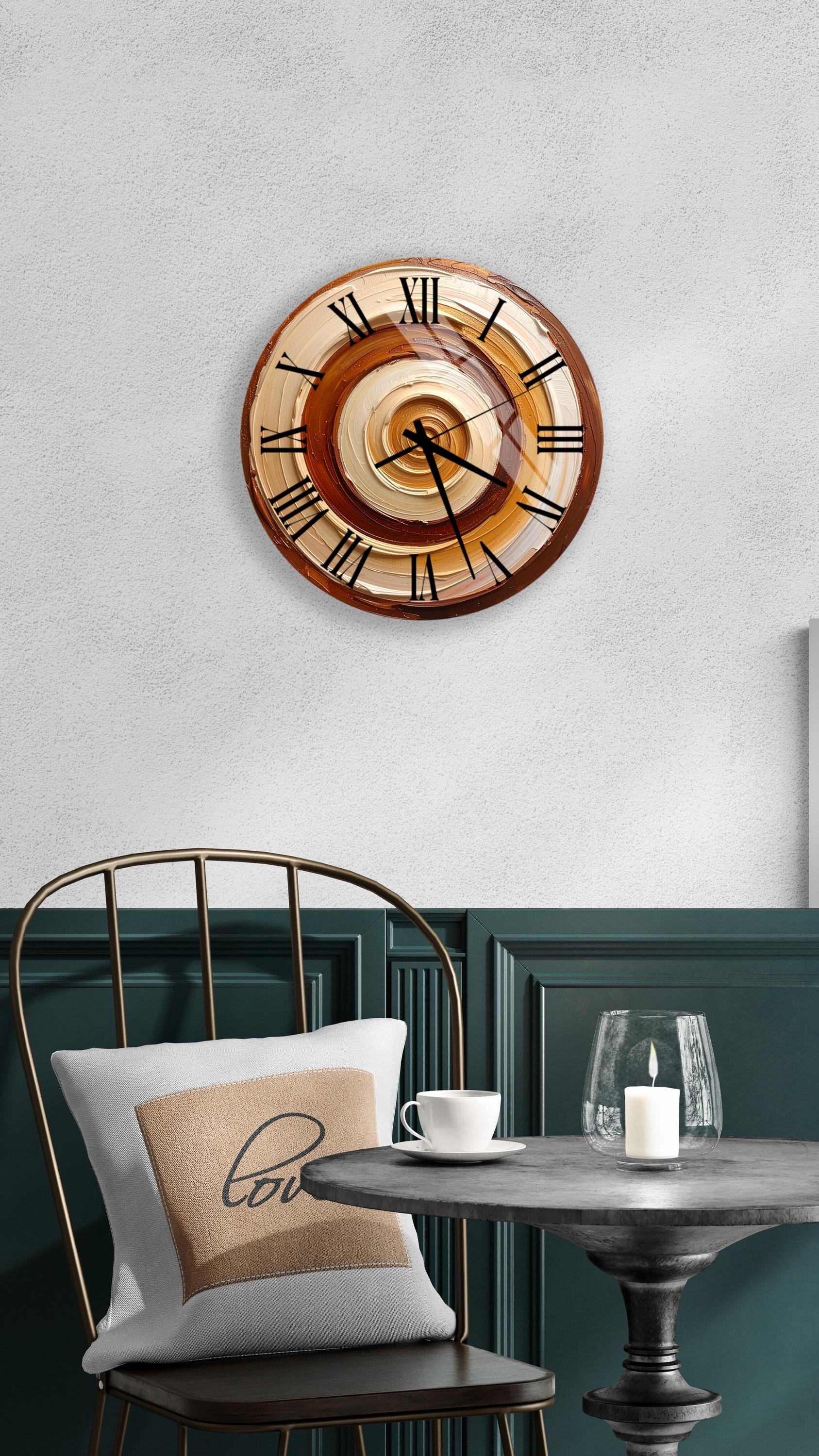 a wall clock with a brown and orange design, mounted on a white wall above a dining table with a white tablecloth. A white cup and a candle are placed on the table, creating a cozy and inviting atmosphere.