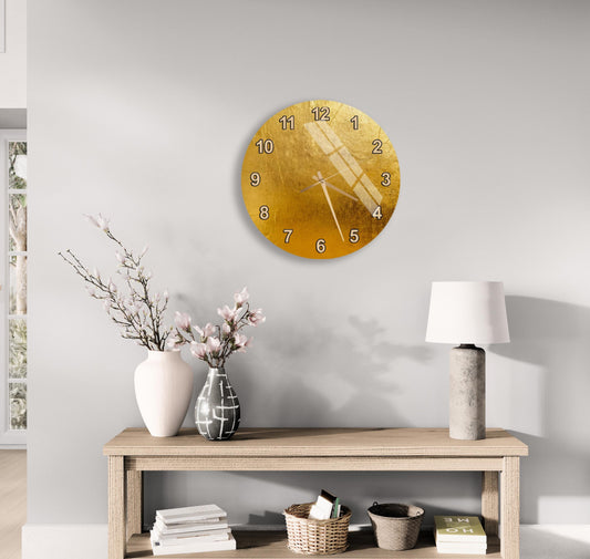 a modern living room with a wooden console table, a round gold wall clock, a white lamp, a vase with pink flowers, and a stack of books.