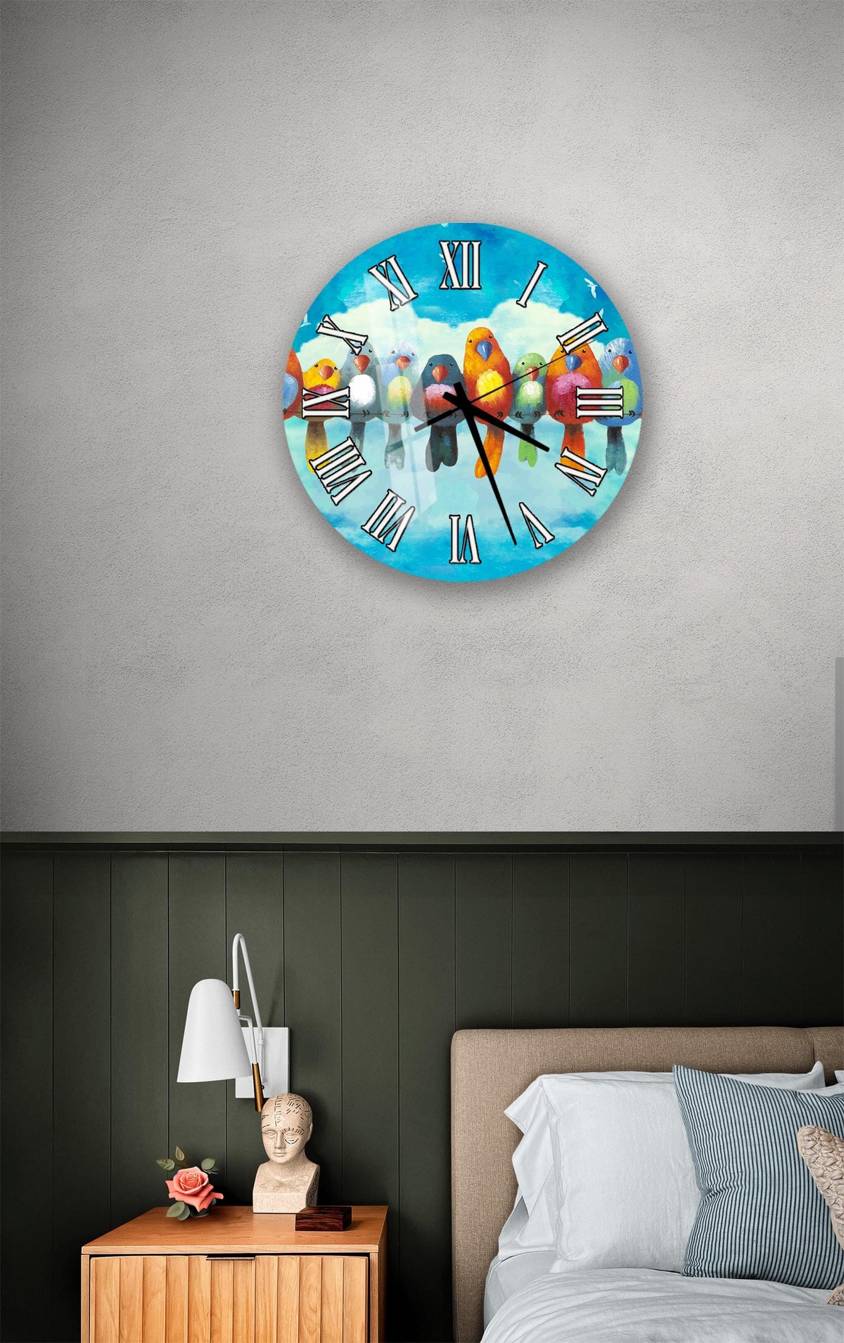 a clock with a bird design on it, mounted on a wall above a bedside table with a lamp and a small statue.