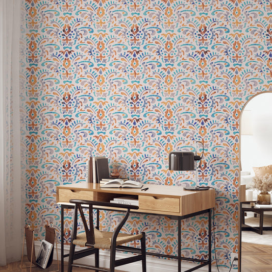 a modern and stylish workspace with a wooden desk, a black chair, and a lamp. The desk is positioned against a wall with a colorful, patterned wallpaper. There are several books and decorative items on the desk, suggesting a well-organized and functional workspace.