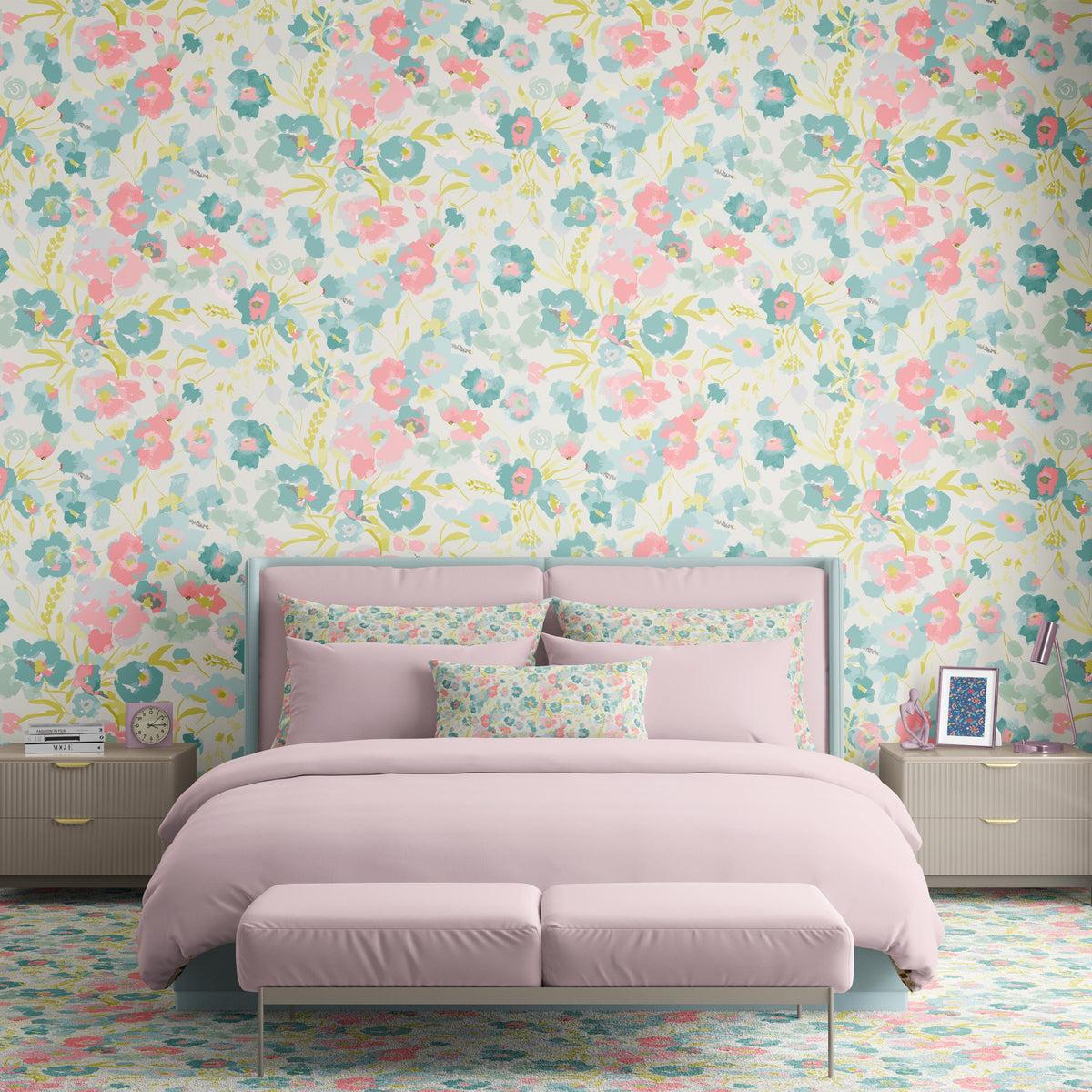 a bedroom with a large floral wallpaper covering the walls. The focal point of the room is a bed with a pink bedspread and matching pillows. The bed is positioned against the wall with a nightstand on either side. The room also features a bench and a lamp, adding to the overall decor.