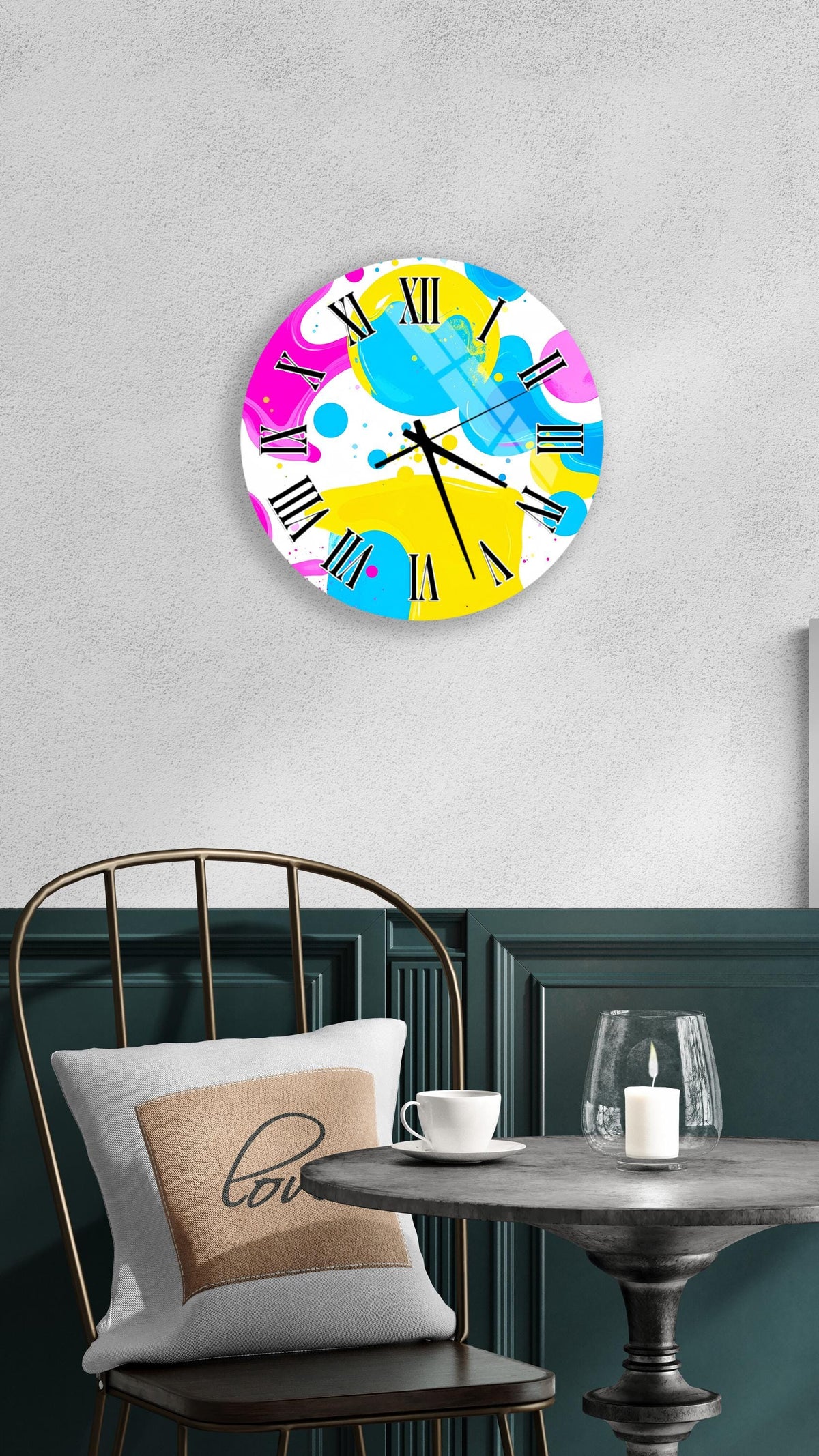 a colorful abstract clock with a white face and black hands, hanging on a wall above a table with a white tablecloth.