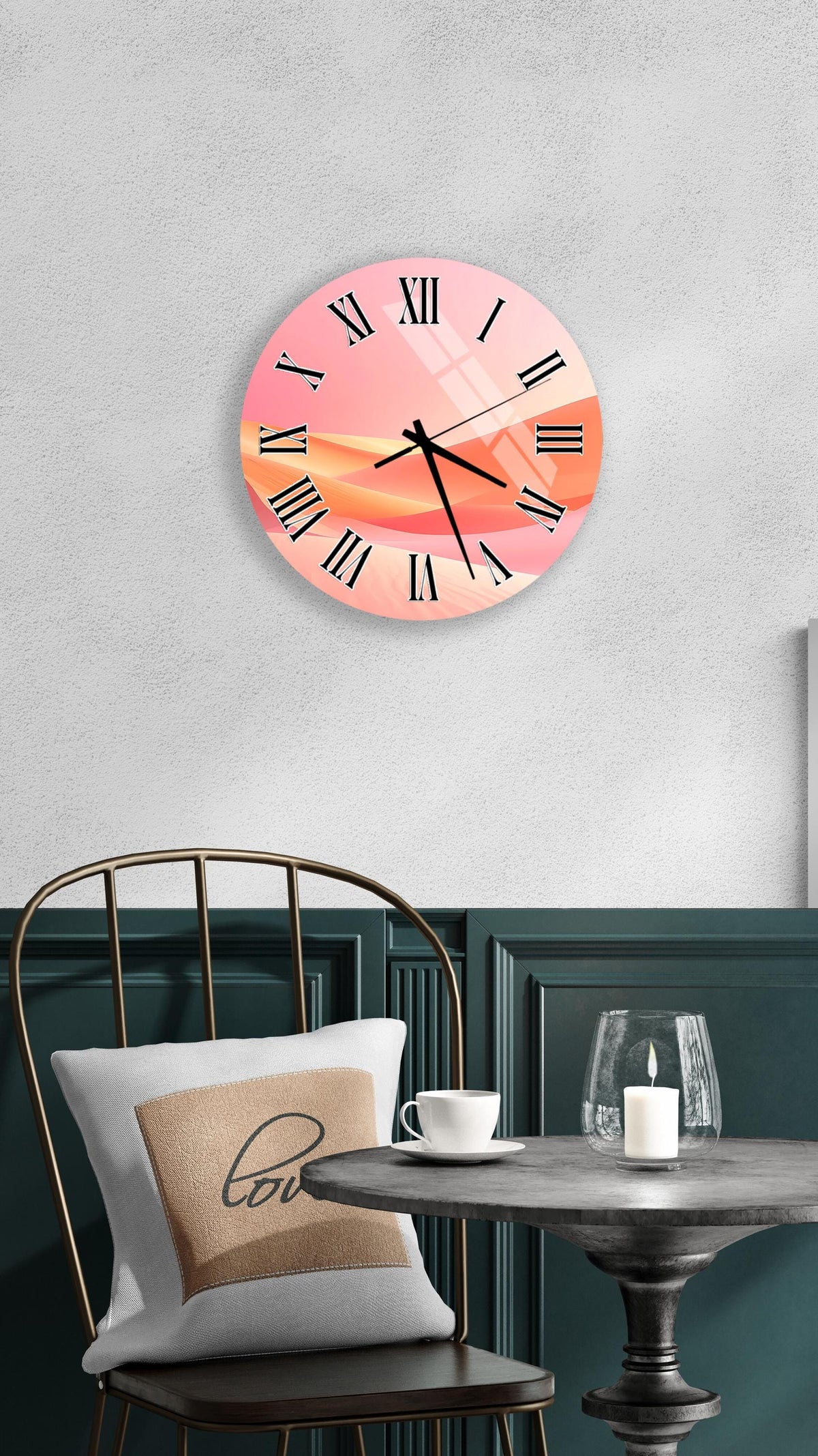 a wall clock with a pink and orange abstract design, mounted on a wall above a table with a white tablecloth. The table has a glass candle and a white coffee cup on it.