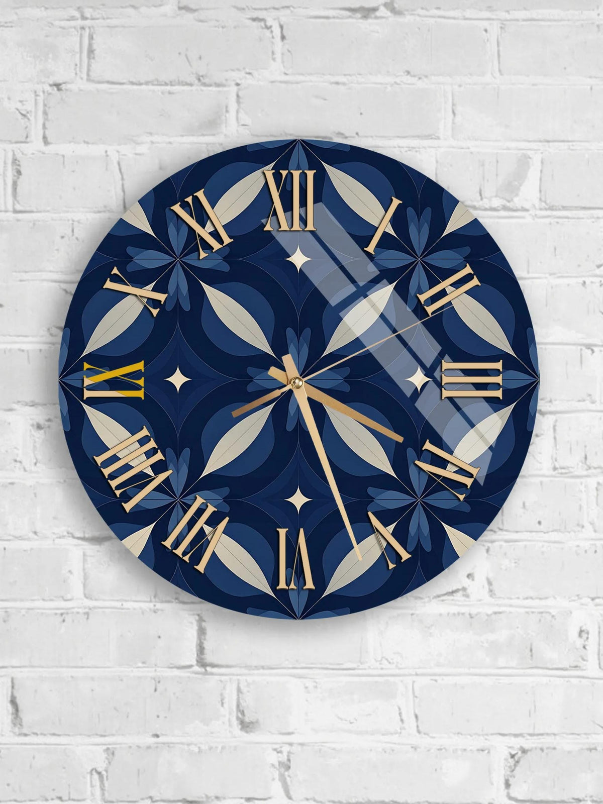 A round wall clock with a blue and gold design, mounted on a white brick wall.