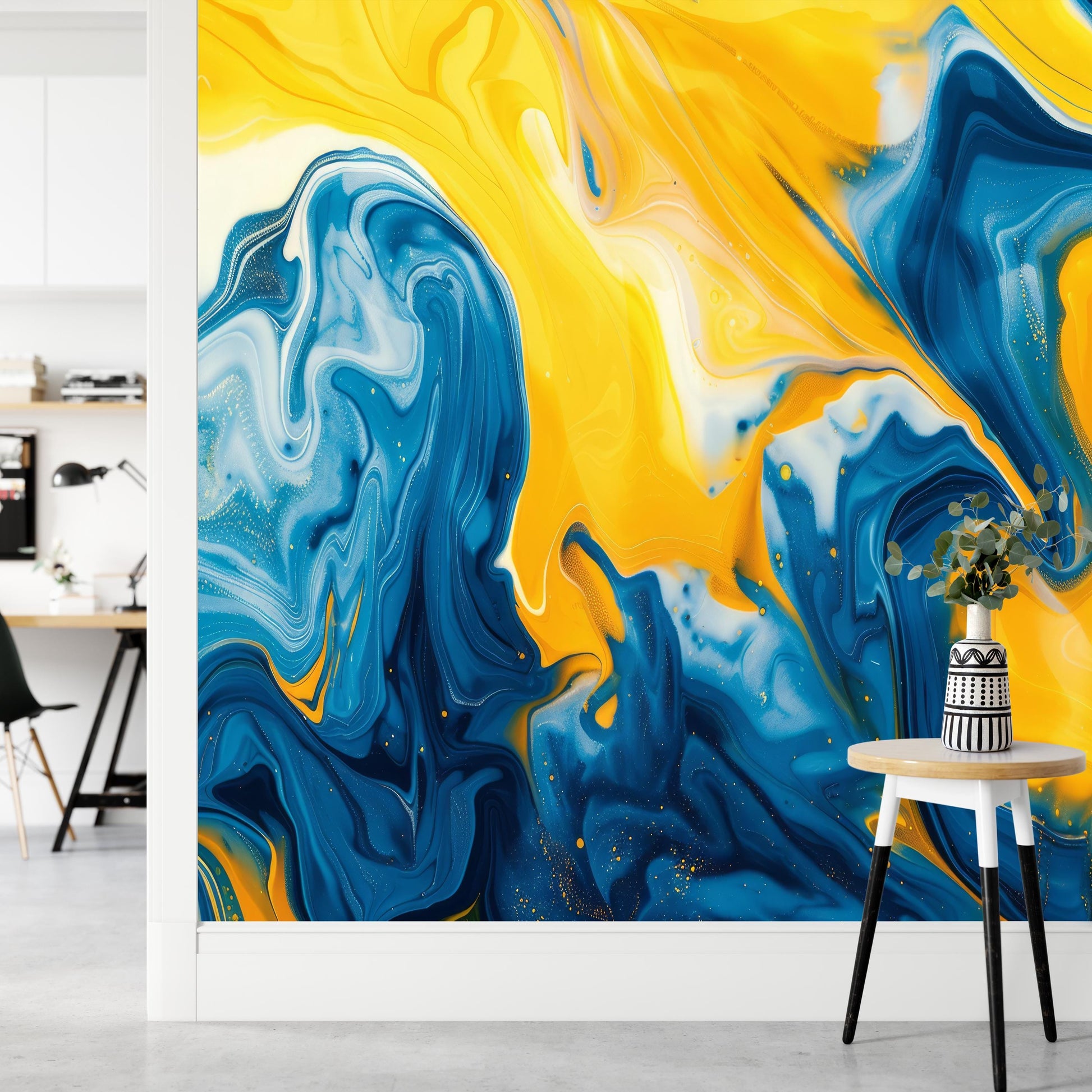 a vibrant and abstract mural with swirling patterns of blue and yellow hues, creating a dynamic and energetic visual effect. The mural is set against a white wall, and a small table with a vase of flowers is positioned in front of it, adding a touch of natural beauty to the scene.