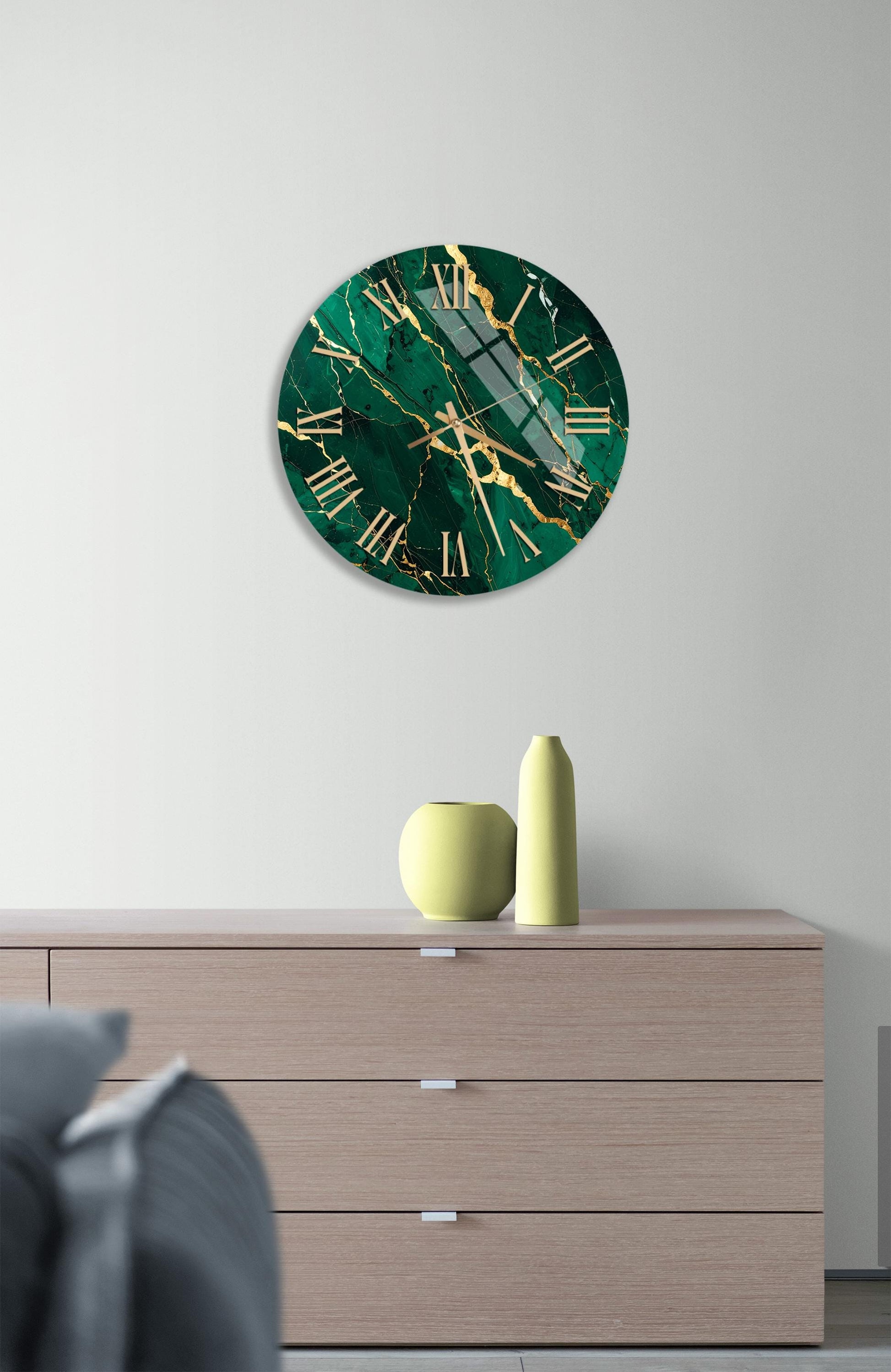 a modern living room with a large green marble clock hanging on the wall above a wooden dresser. The dresser has three drawers and a vase on top.