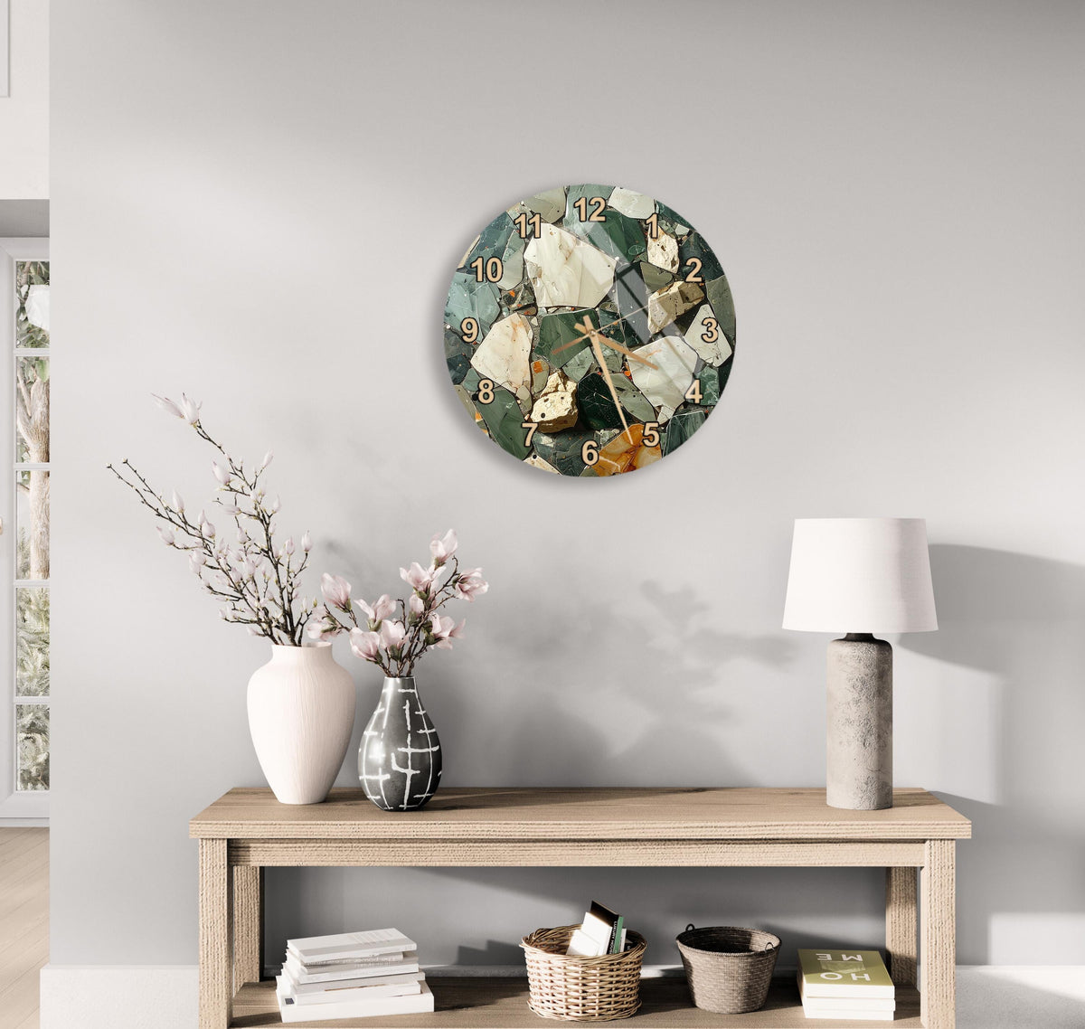 a modern living room with a wooden console table, a round wall clock with a mosaic design, a vase with pink flowers, and a lamp on the table.