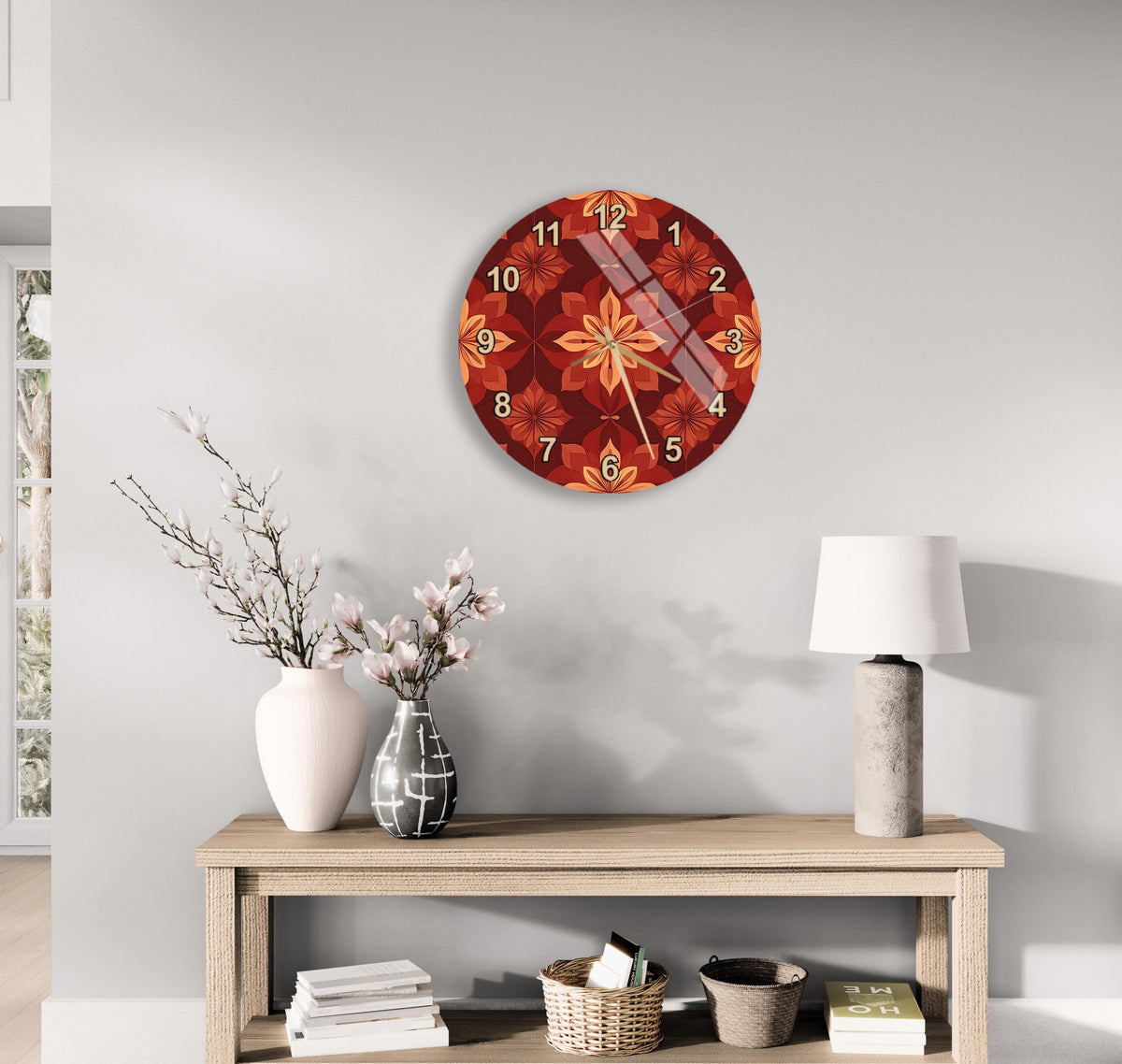a wall clock with a floral design, a wooden table with a lamp, a vase with flowers, and some books on a shelf.