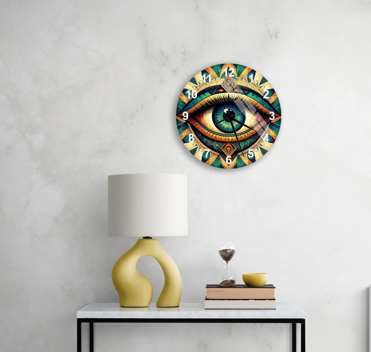 a wall clock with a colorful, eye-catching design, a yellow table lamp, a stack of books, and a glass of wine on a white table.