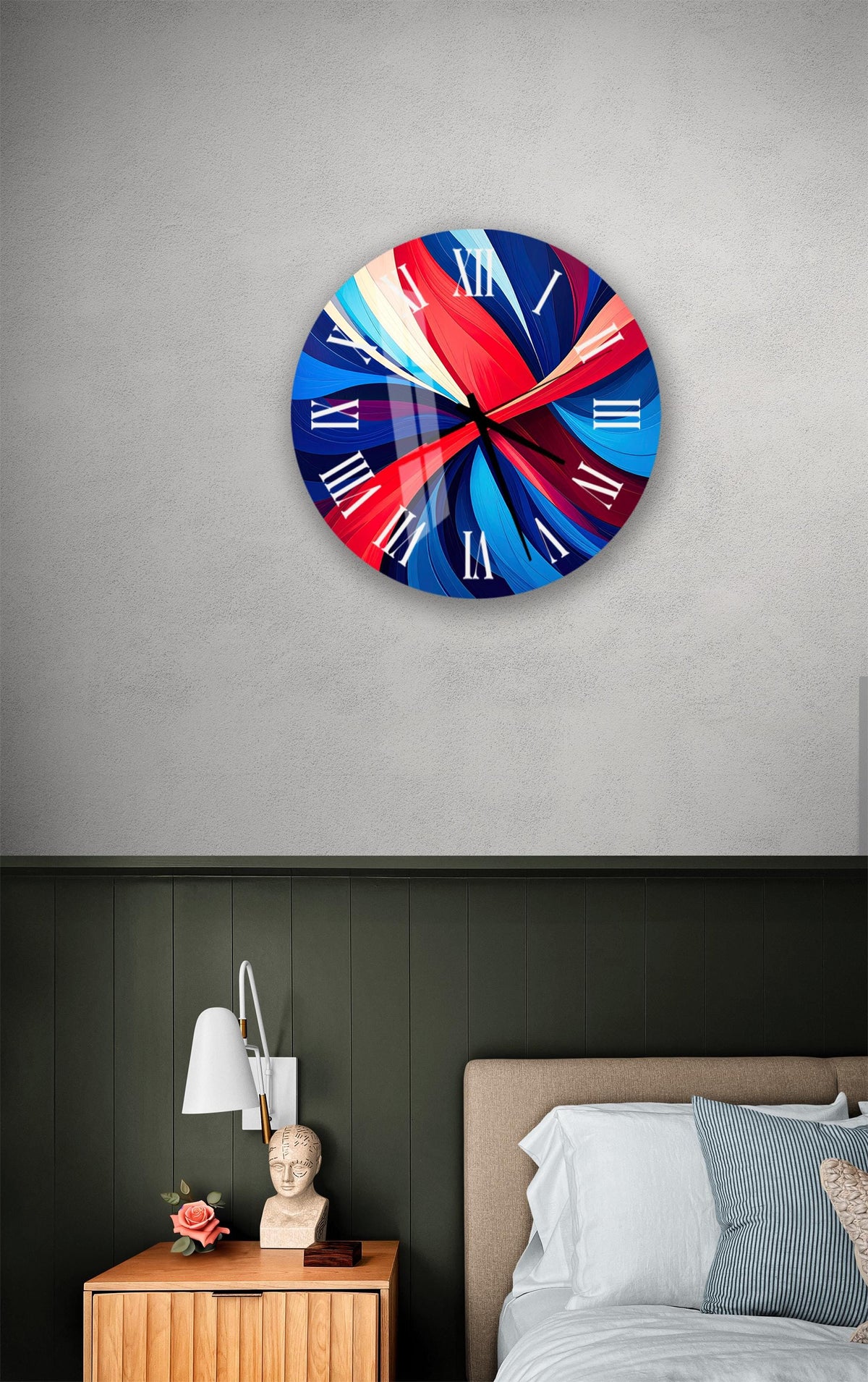 a modern bedroom with a large, colorful clock on the wall above a bed. The clock has a vibrant design with red, blue, and white colors. The room also includes a nightstand with a lamp and a small statue, as well as a striped pillow on the bed.