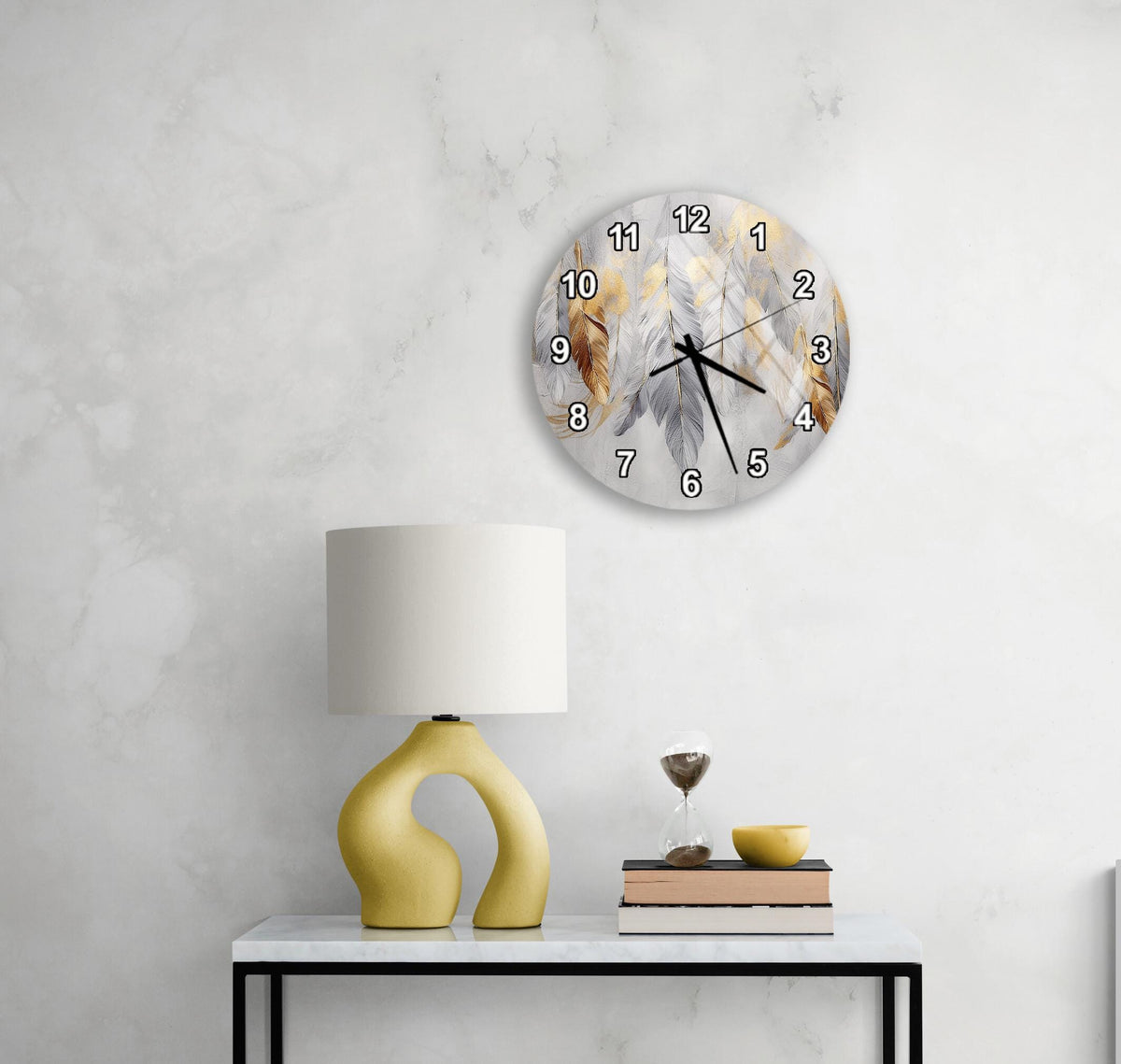 a modern living room with a white marble wall, a round wall clock with a feather design, a yellow lamp with a unique curved base, and a small table with a book and a glass of wine.