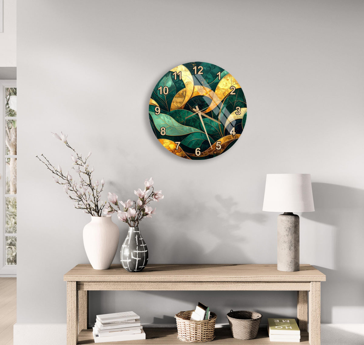a modern living room with a large wall clock displaying a green and gold design, a wooden table with a lamp, a vase with flowers, and a stack of books.