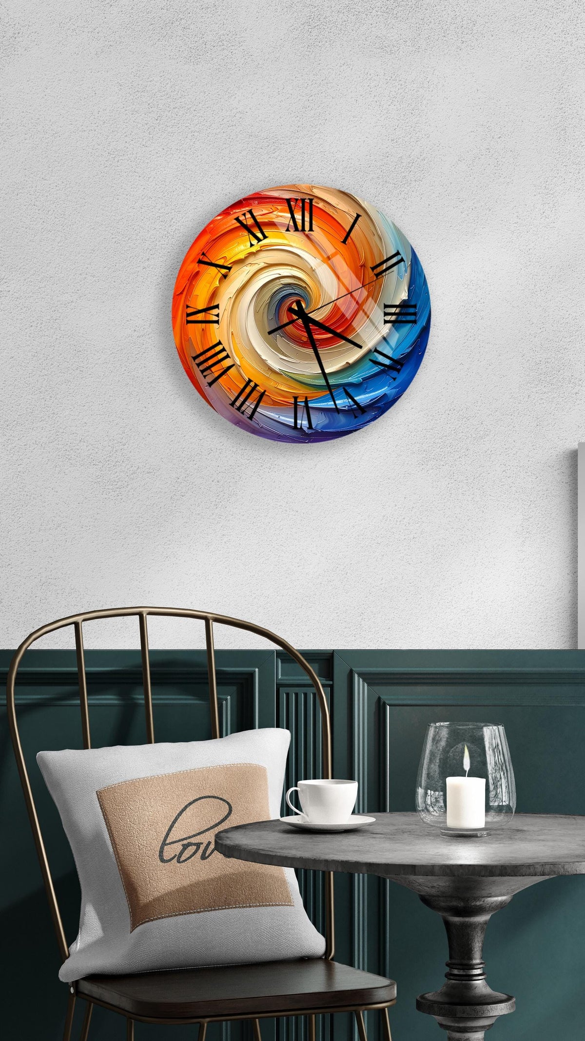 a round clock with a colorful spiral design on a white wall, accompanied by a black metal chair, a white table with a candle, and a beige pillow with the word "love" on it.