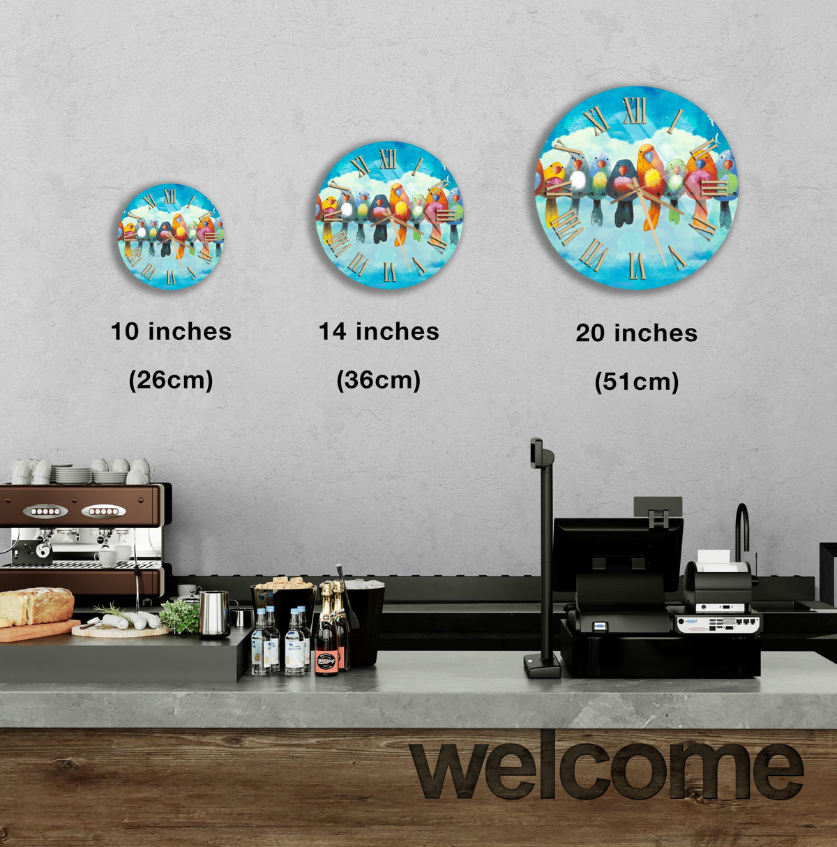 a counter with a cash register, a coffee machine, and a sign that says "welcome". There are three clock-like images of birds on the counter, each at a different size, ranging from 10 inches to 20 inches.