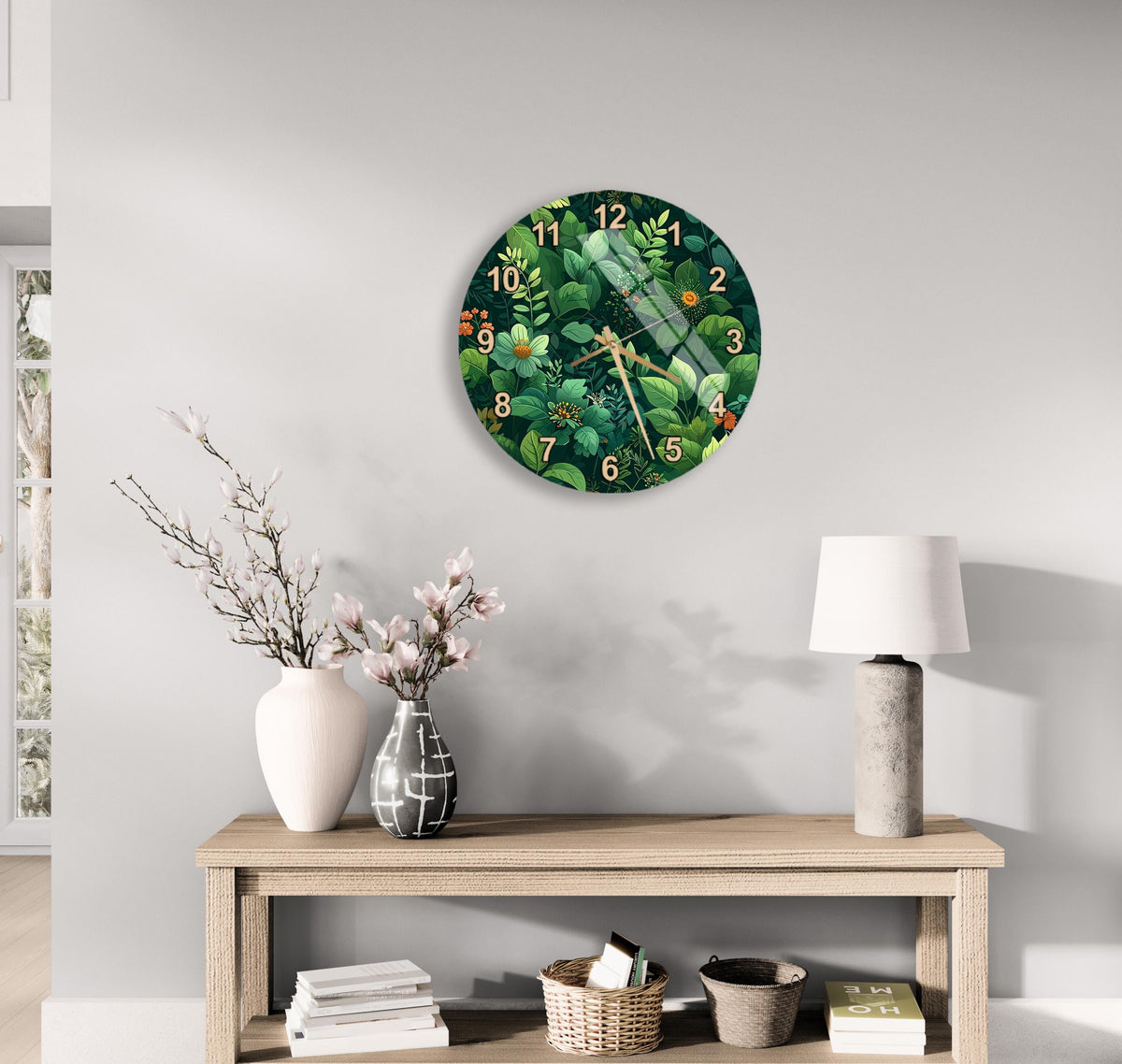 a clock with a green and white floral design hanging on a wall above a wooden table with various decorative items, including a vase with flowers, a lamp, and a stack of books.
