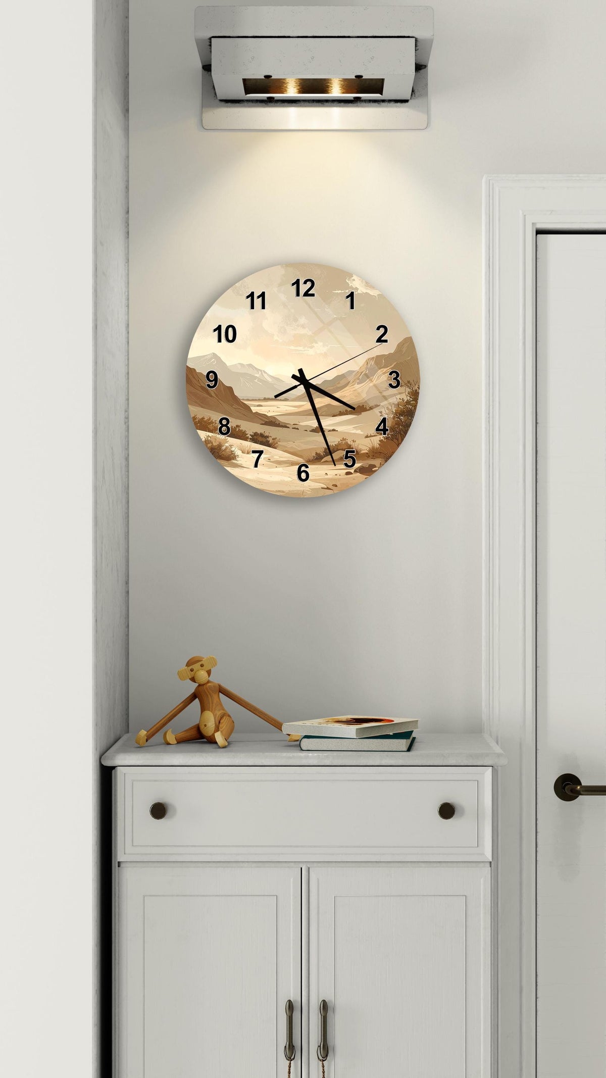 a wall clock with a landscape scene on its face, mounted on a white wall above a white cabinet.