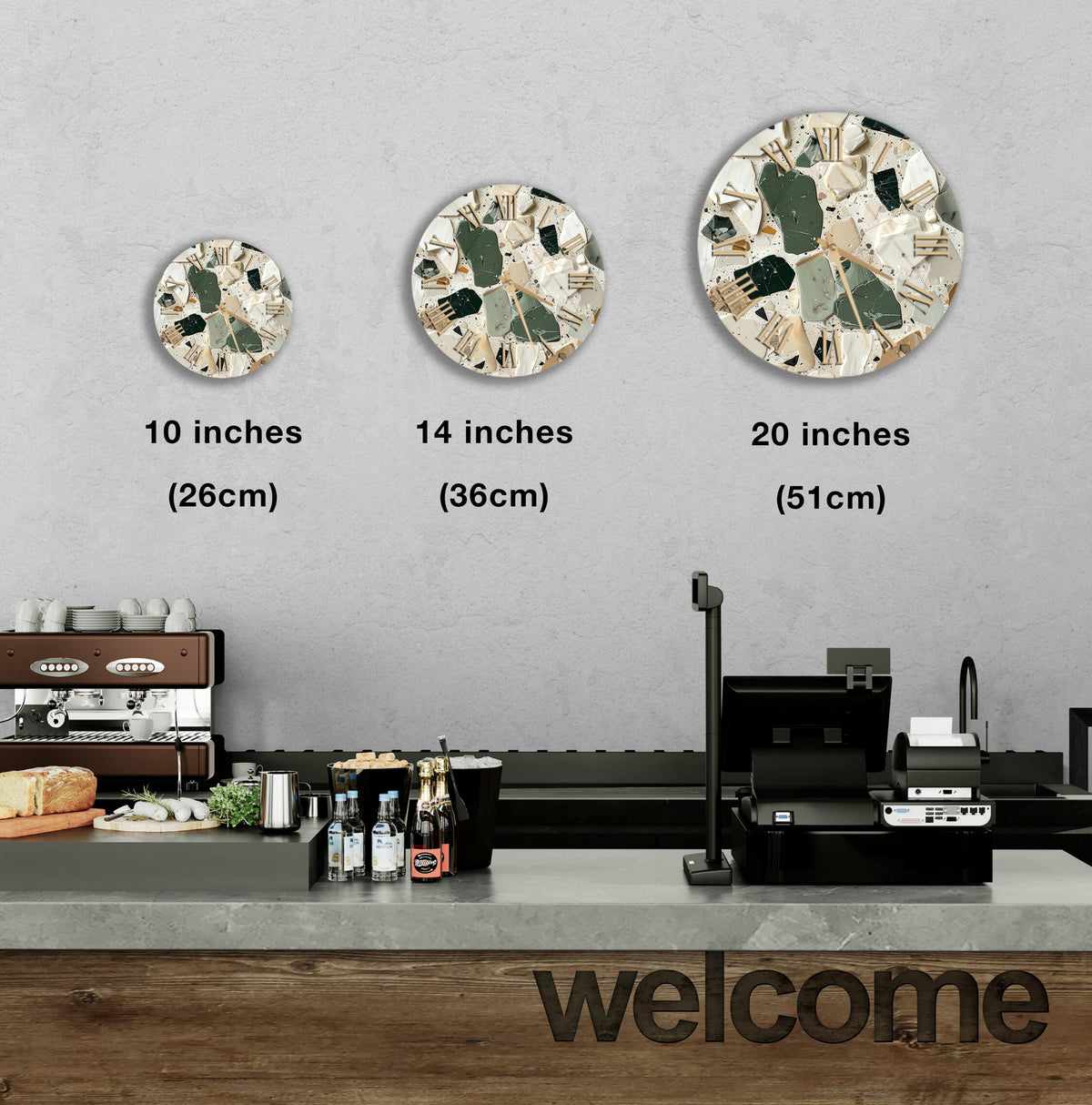 a counter in a restaurant with three different sizes of round wall clocks displayed above it. The clocks are of varying sizes, ranging from 10 inches to 20 inches in diameter. The counter also has various items such as bottles and a cash register, indicating that it is a part of the restaurant's service area. The word "welcome" is written on the counter, suggesting that the restaurant is ready to welcome customers.