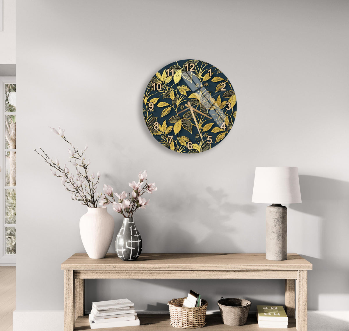 a modern living room with a wooden console table, a round wall clock with a gold leaf design, a white vase with pink flowers, and a white lamp on a side table.