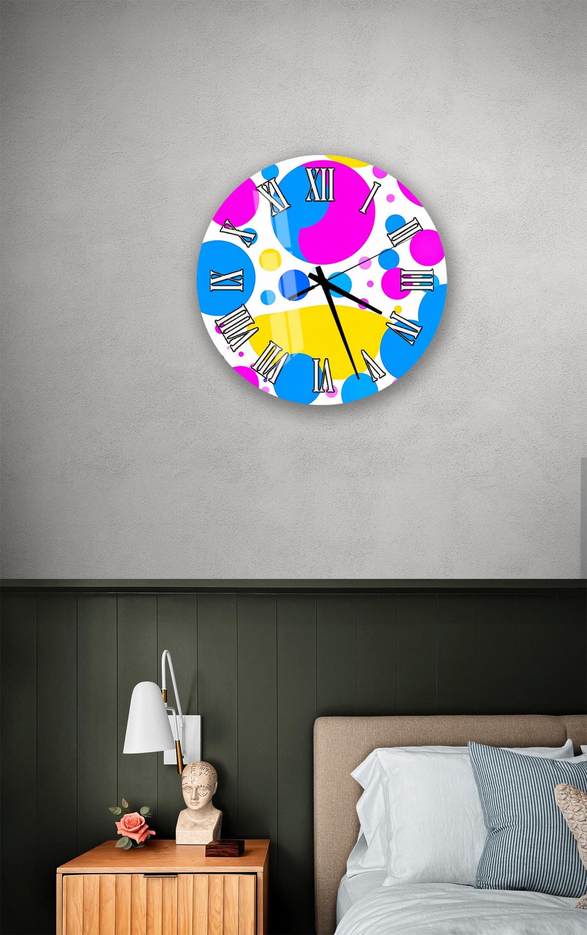 a bedroom setting with a colorful wall clock, a wooden nightstand, and a bed with white pillows.