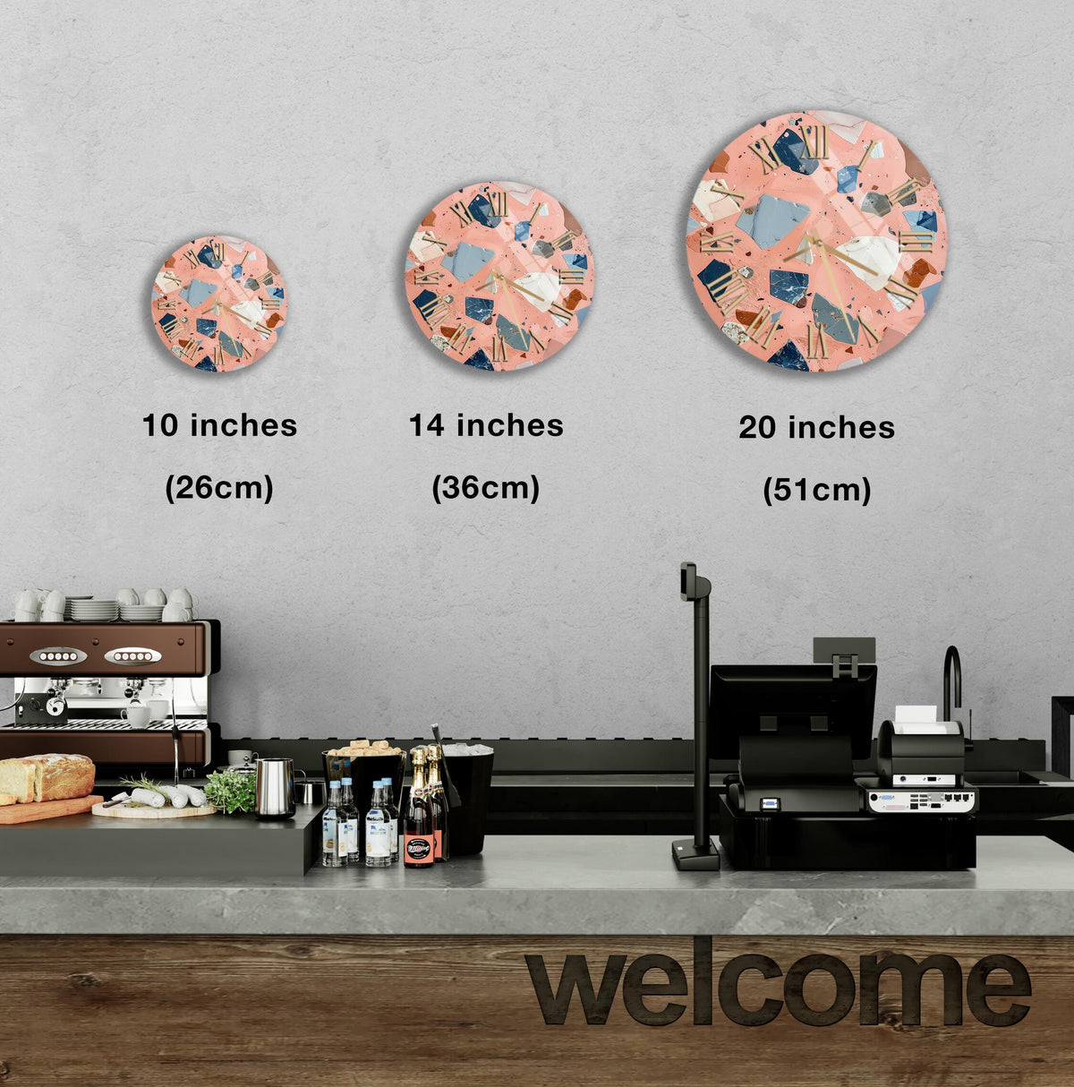 a counter in a restaurant with a welcome sign, and three different sizes of circular wall art displayed above the counter.