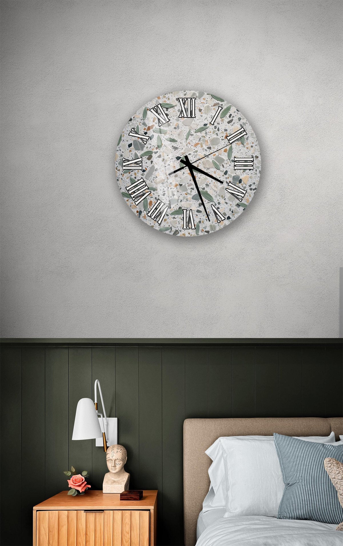 a bedroom setting with a round wall clock displaying Roman numerals, a wooden nightstand with a lamp, and a bed with white bedding.