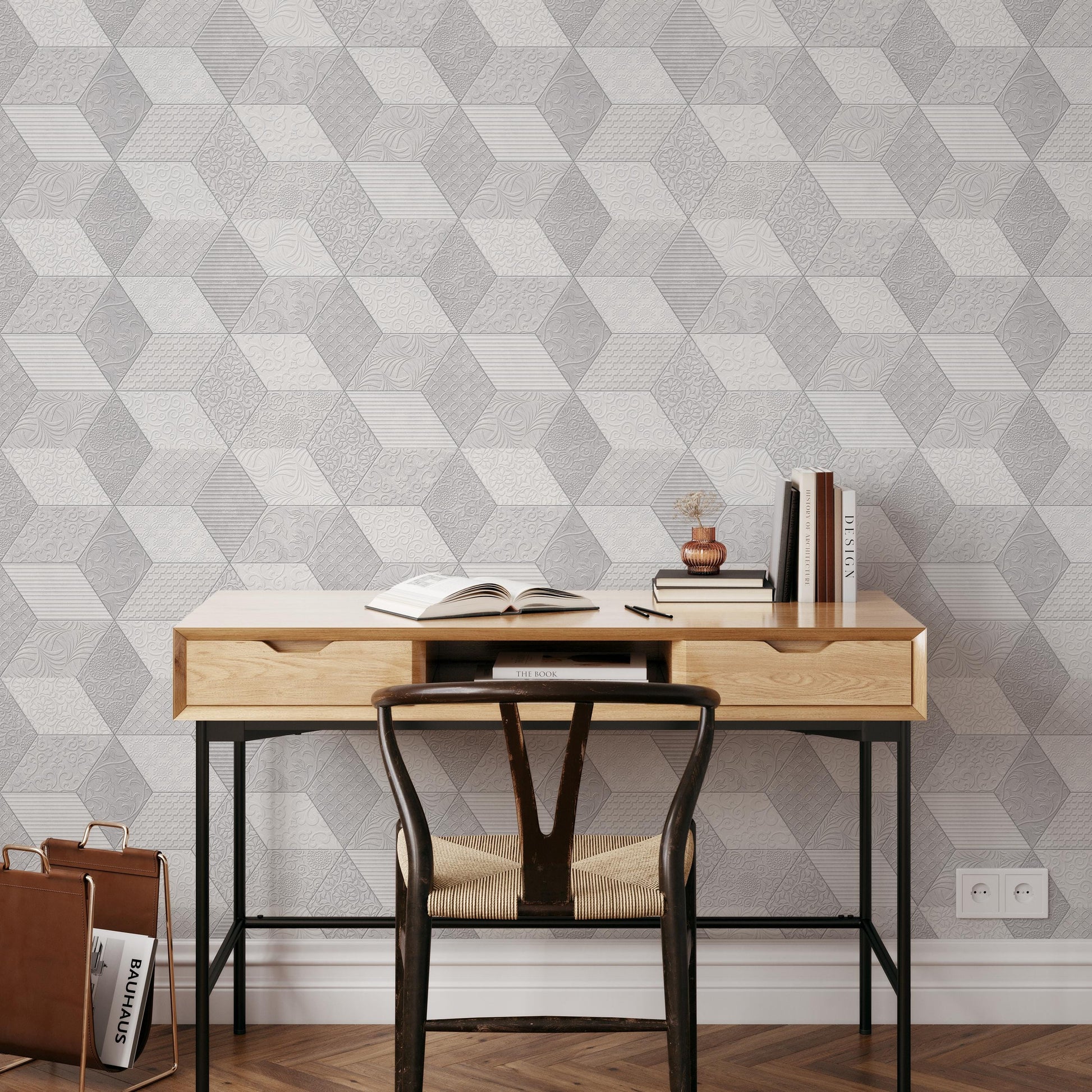 a modern workspace with a wooden desk, a black chair, and a geometric patterned wallpaper. On the desk, there are a few books, a pen, and a small plant.