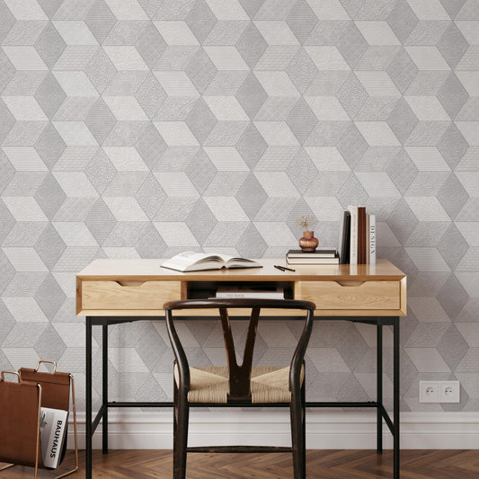 a modern workspace with a wooden desk, a black chair, and a geometric patterned wallpaper. On the desk, there are a few books, a pen, and a small plant.