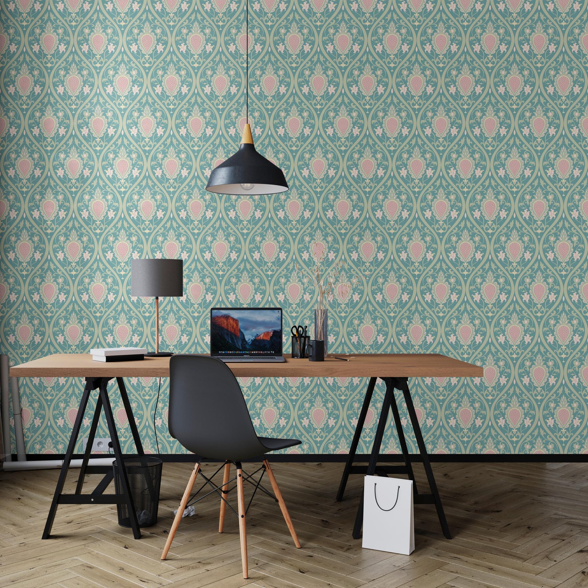 a modern workspace with a wooden desk, a laptop, a black chair, and a lamp. The desk is positioned against a wall with a patterned wallpaper, creating a visually appealing and organized environment.