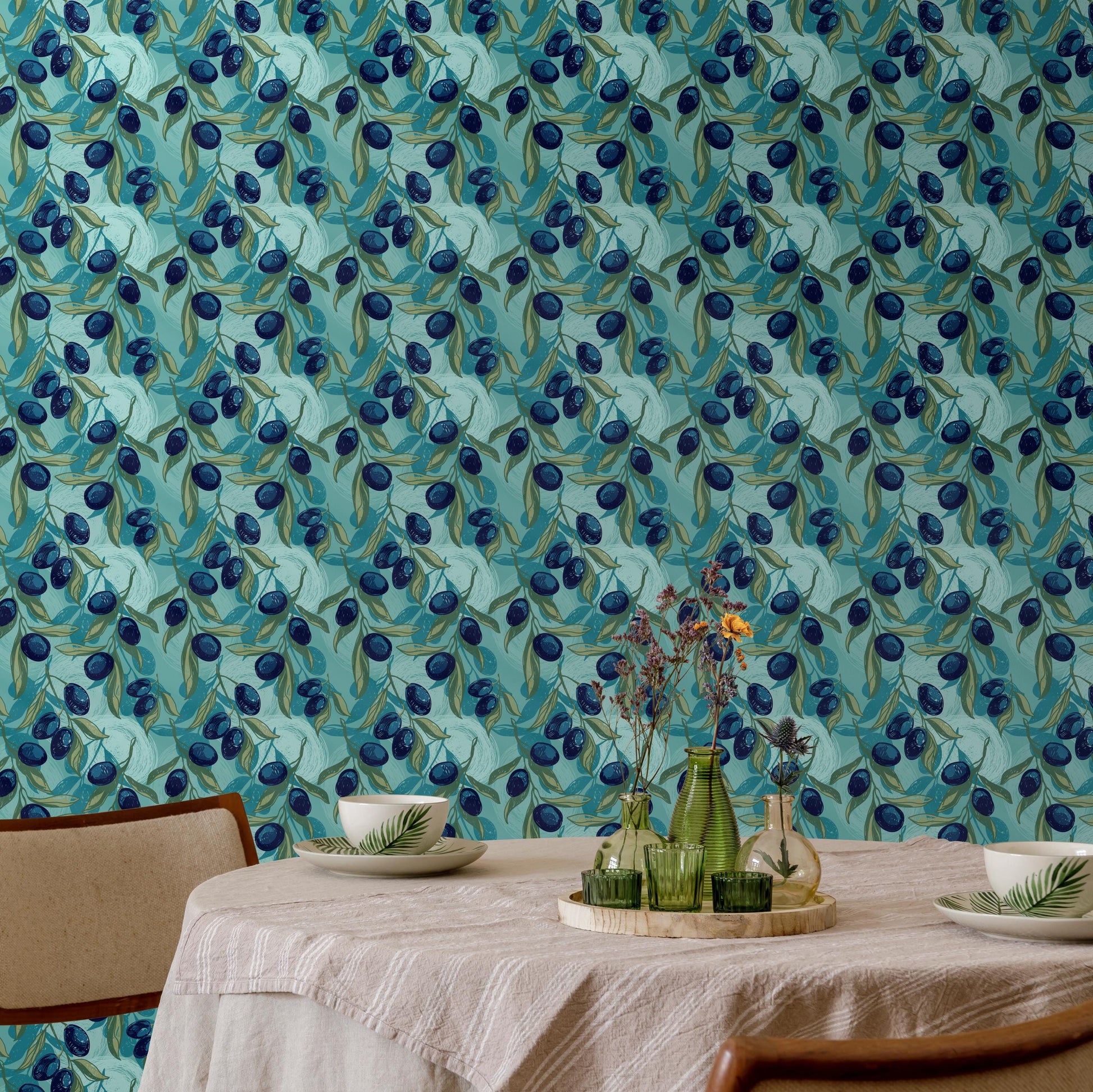 a dining table set with a white tablecloth, two white plates, and two green vases with flowers. The table is positioned against a wall with a blue and green patterned wallpaper.