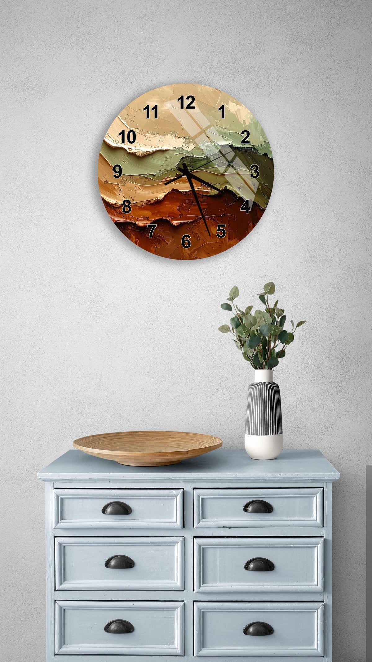 a wall clock with a colorful design, a wooden tray, a vase with greenery, and a gray dresser with six drawers.