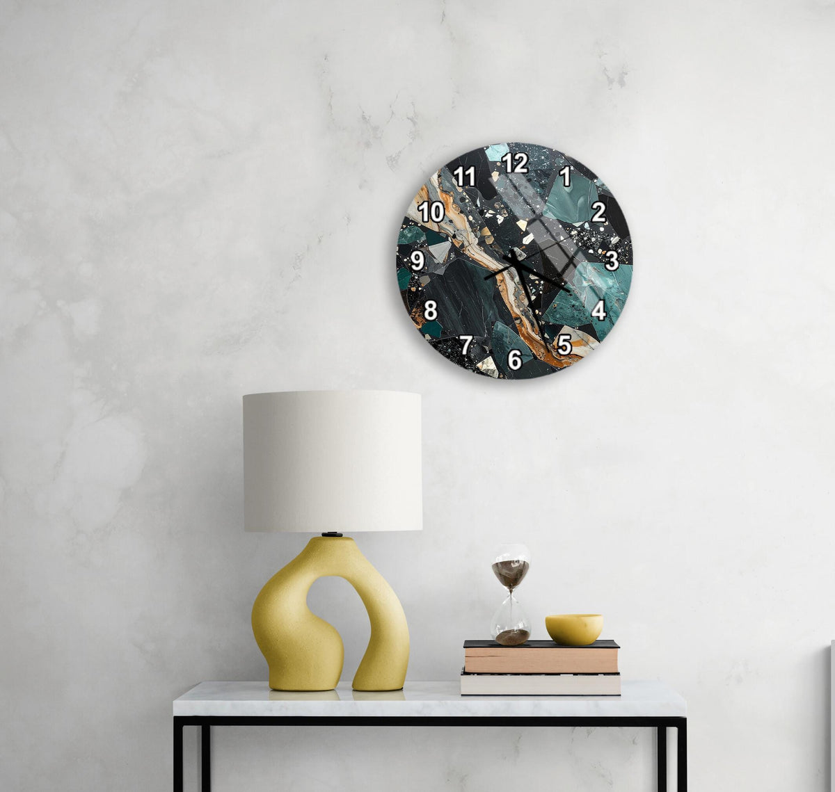 a modern, abstract clock with a blue and gold color scheme, mounted on a wall above a white table with a yellow lamp and a stack of books.