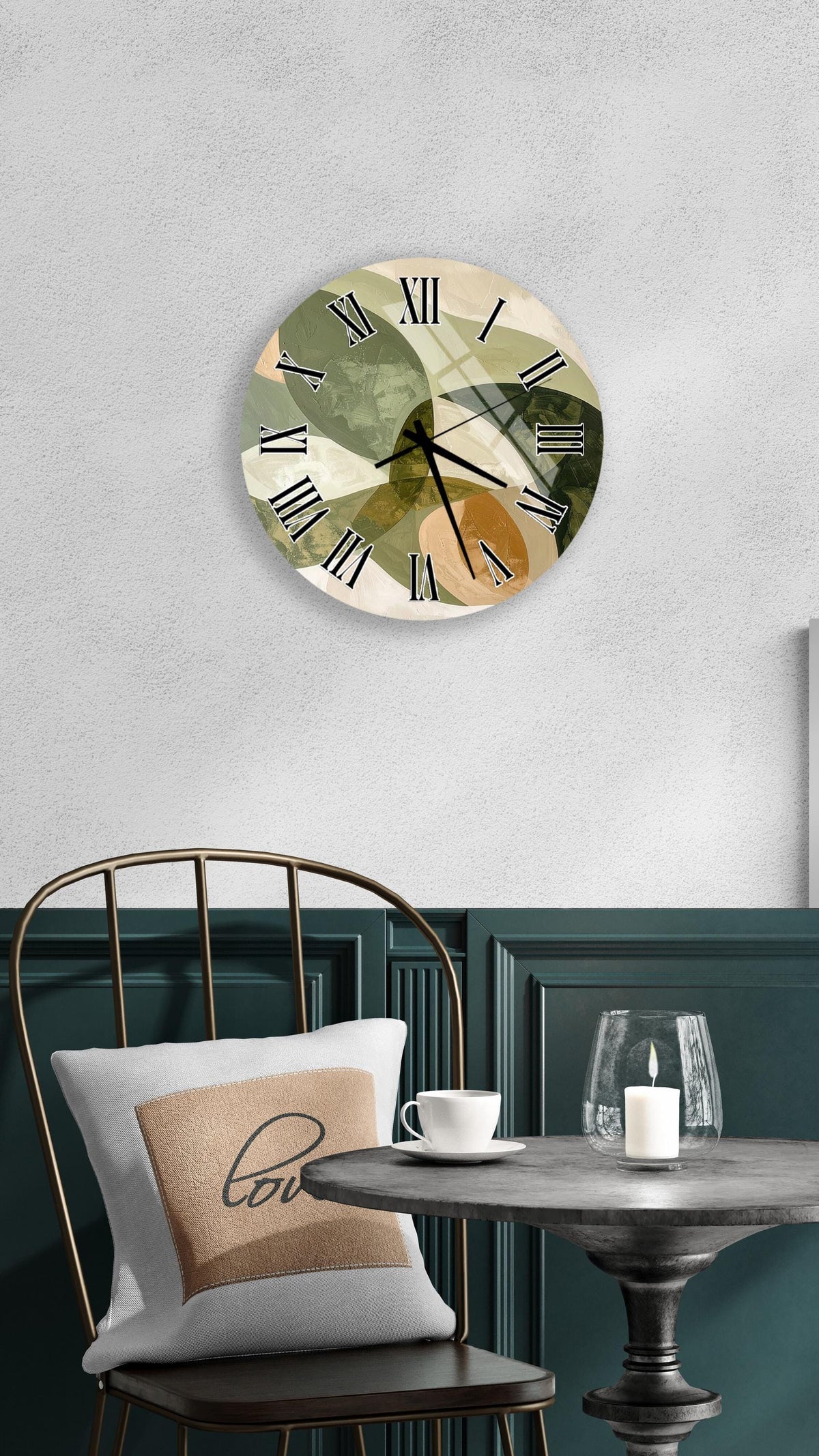 a wall clock with a unique abstract design, a white table with a candle and a cup, and a green chair with a pillow.