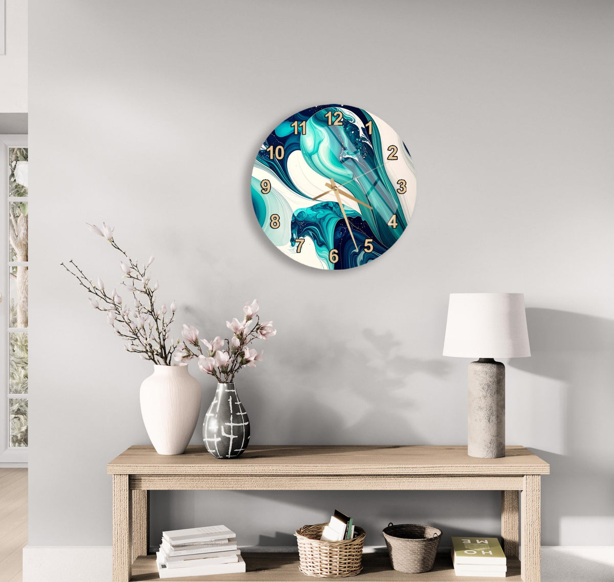 a modern living room with a round wall clock displaying a blue and white abstract design, a wooden table with a lamp, a vase with pink flowers, and a stack of books.