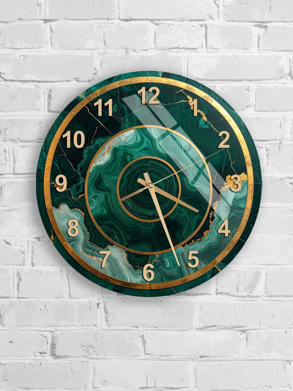 A wall clock with a green marble-like design and gold accents, mounted on a white brick wall.