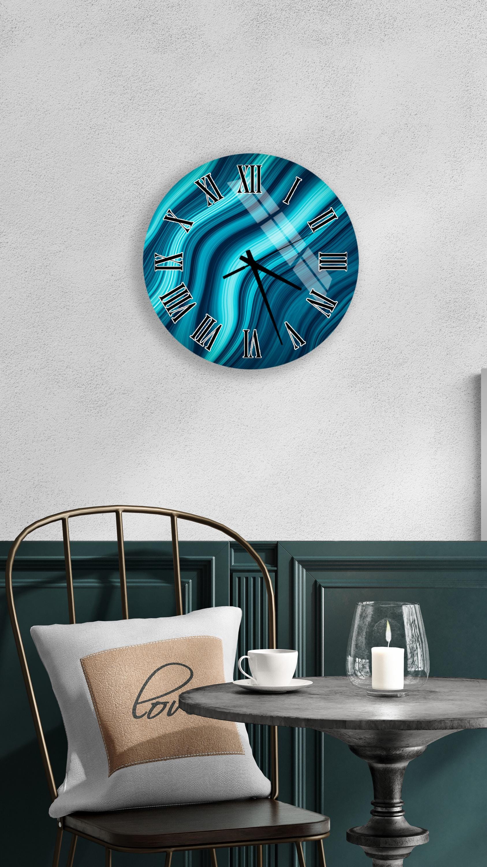 a modern interior design with a round wall clock featuring a blue and white swirl pattern, a white table with a candle and a glass, and a black metal chair with a white pillow.
