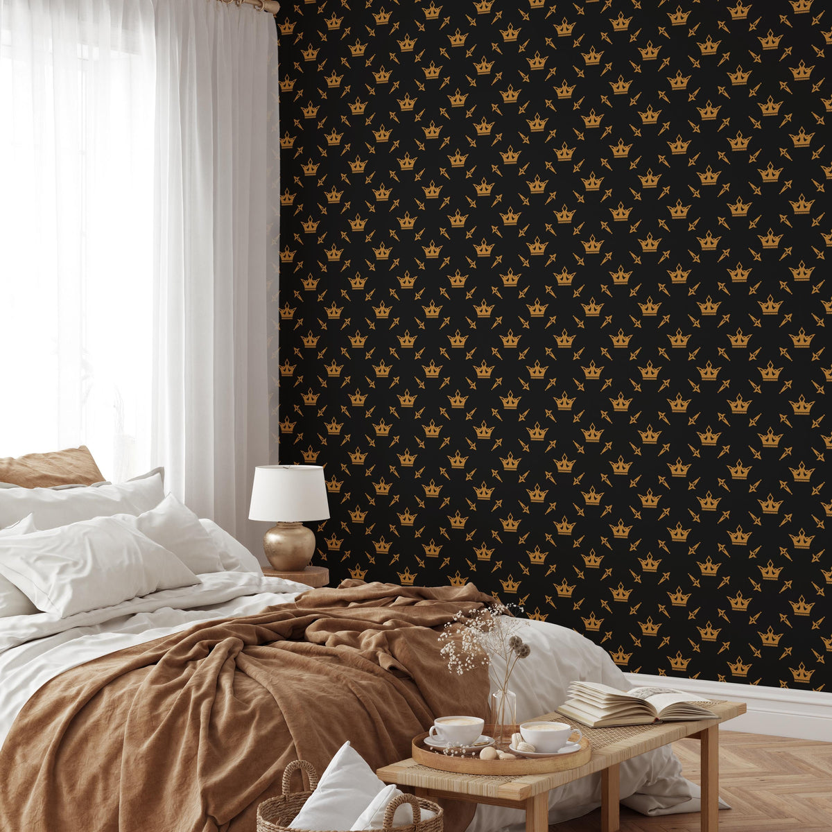 a bedroom with a bed, a nightstand, and a wooden table with a vase of flowers. The wall behind the bed has a black and gold pattern with a repeating crown design.