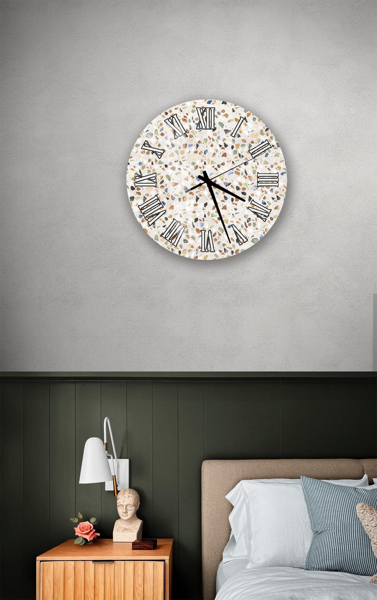 a bedroom setting with a round wall clock displaying a patterned design, a wooden nightstand with a lamp, and a bed with white bedding.