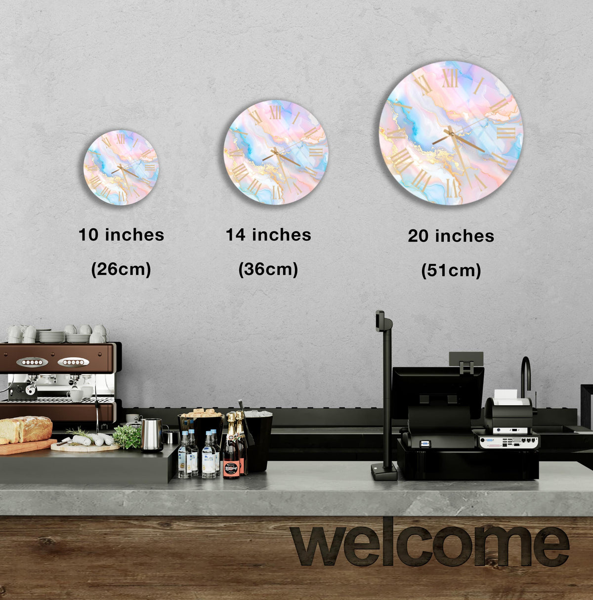 a wall with three round wall clocks of different sizes, each displaying a different time. Below the clocks, there is a counter with various items such as bottles and a sandwich. The word "welcome" is written on the counter.