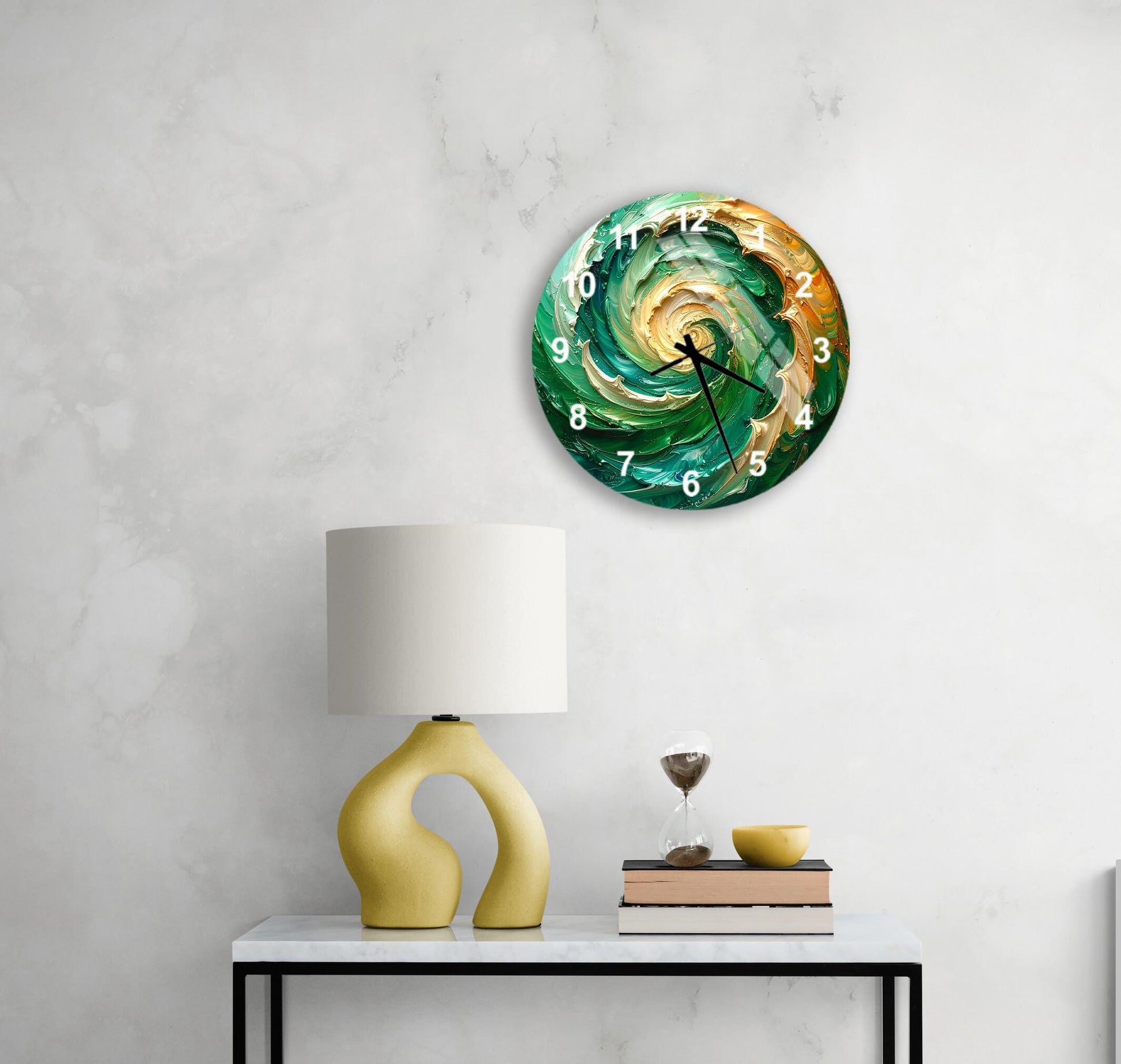 a modern, abstract clock with a swirling green and orange design, mounted on a wall above a white table with a yellow lamp and a stack of books.