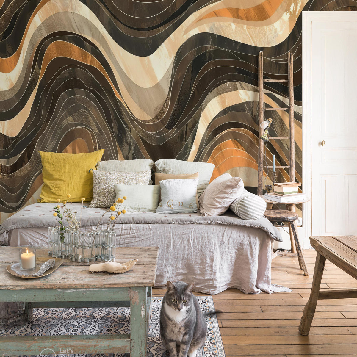 a cozy living room with a large abstract wall mural featuring wavy lines in various shades of brown, orange, and beige. The room is furnished with a gray sofa adorned with yellow and white pillows, a wooden coffee table, and a wooden ladder. A cat is sitting on the floor in front of the sofa, and a vase of flowers is placed on the coffee table.