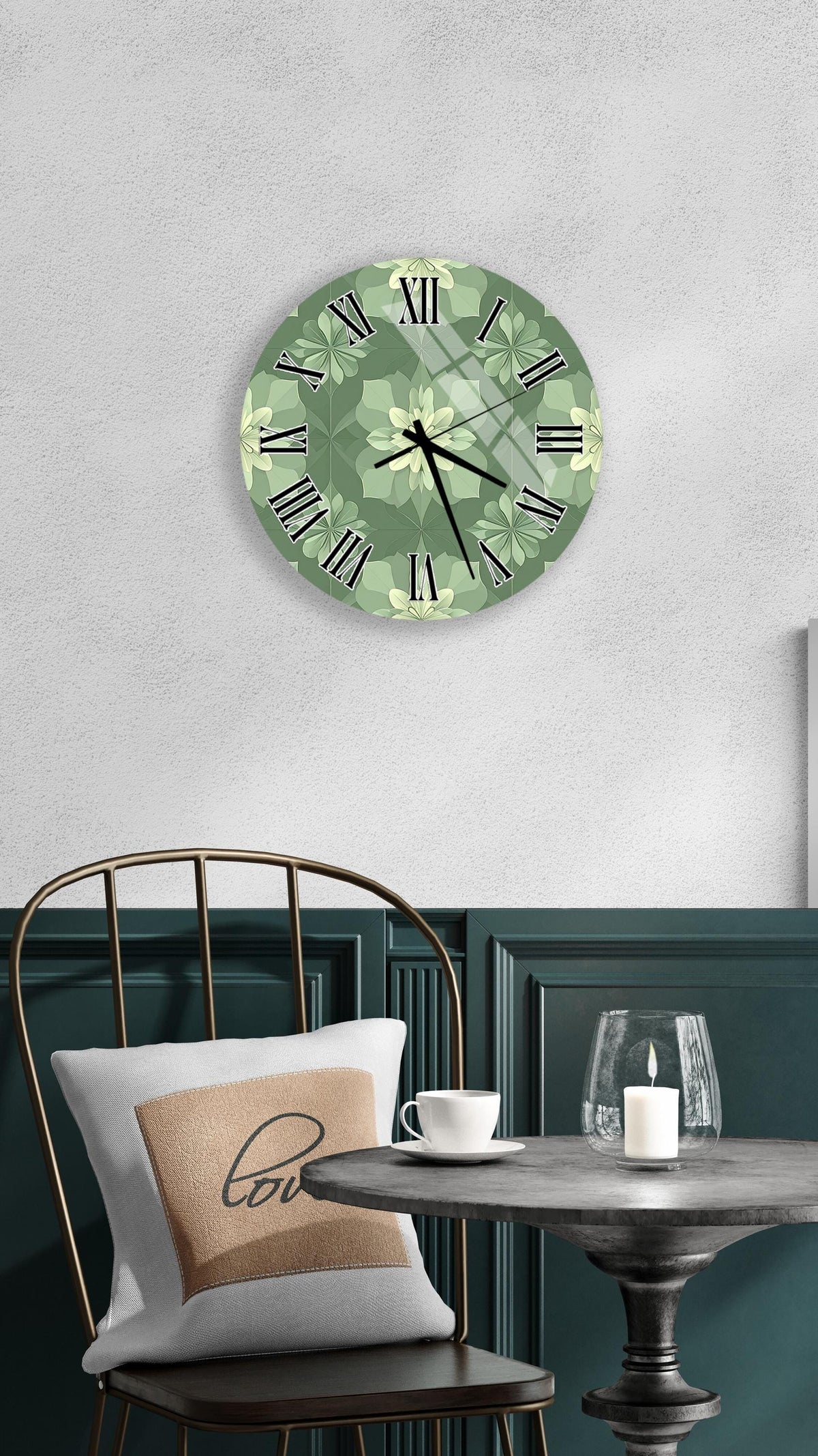 a wall clock with a green floral design, a white table with a candle and a cup, and a black chair with a pillow.