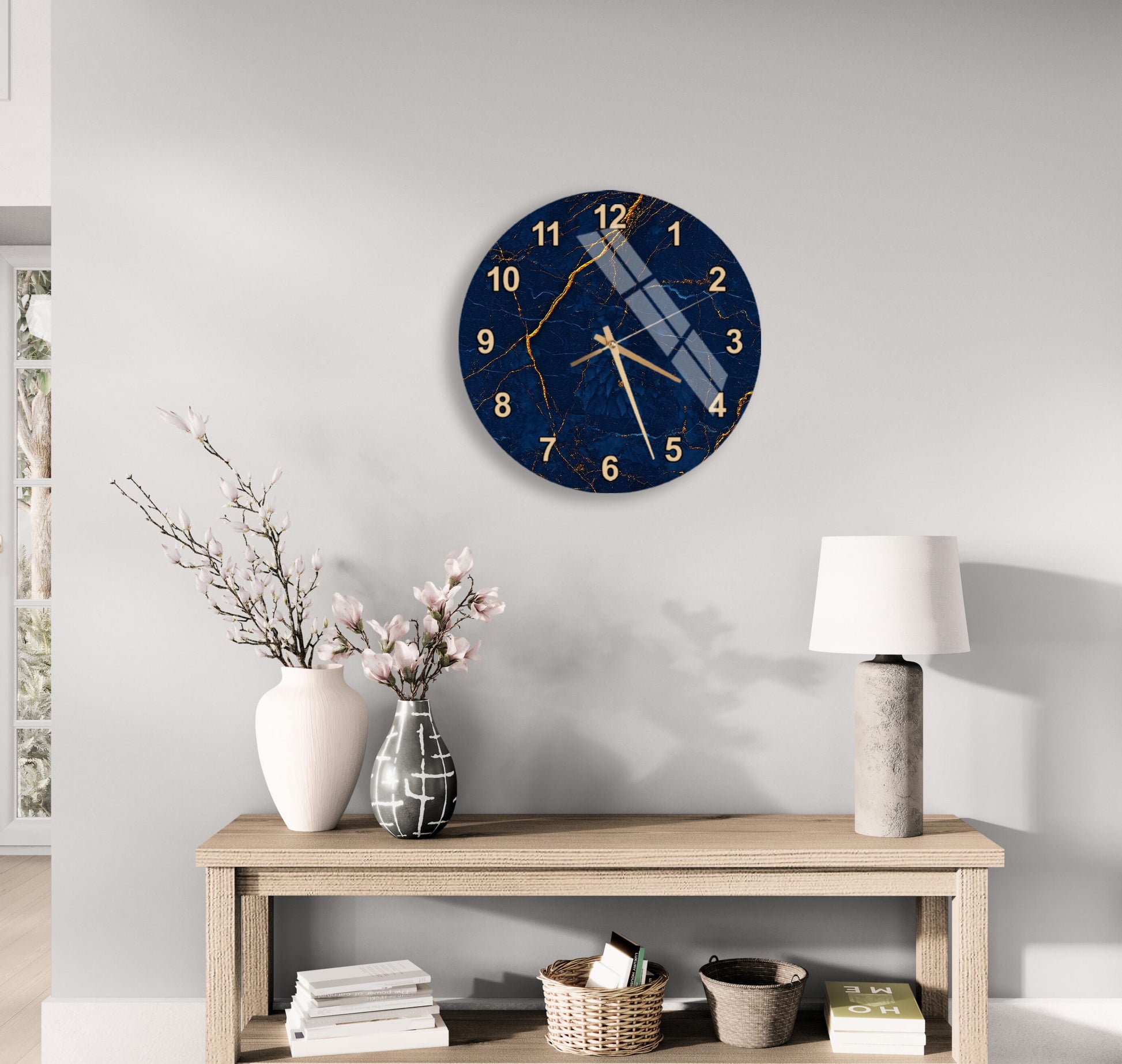 a modern living room with a wooden table, a round wall clock with a blue and gold design, a white vase with pink flowers, and a white lamp on a side table.
