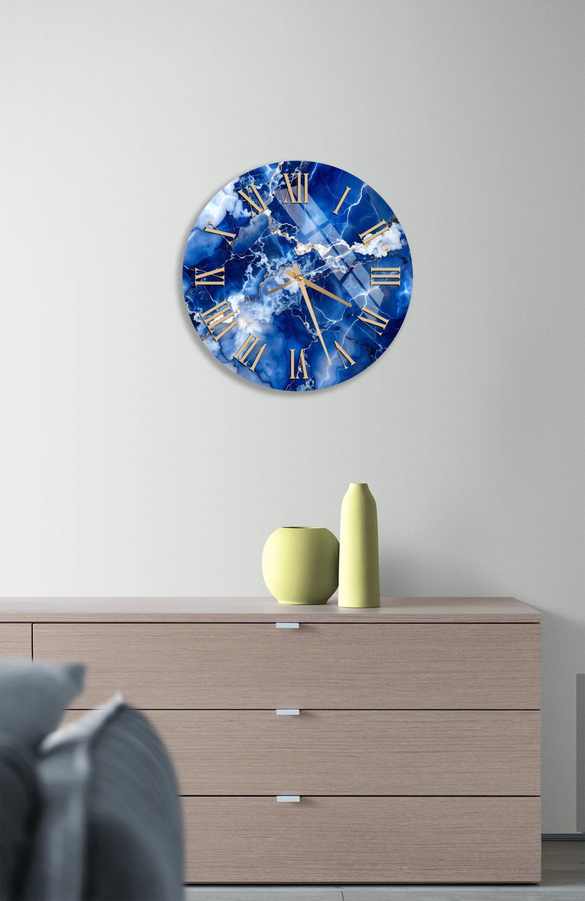 a wall clock with a blue and white marble design, mounted on a wall above a wooden dresser with three drawers.