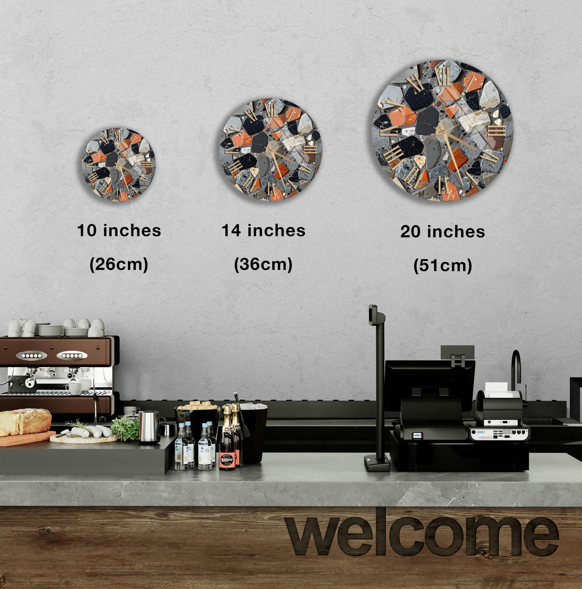 a counter in a restaurant with a "welcome" sign, and three different sizes of circular wall art displayed above the counter.
