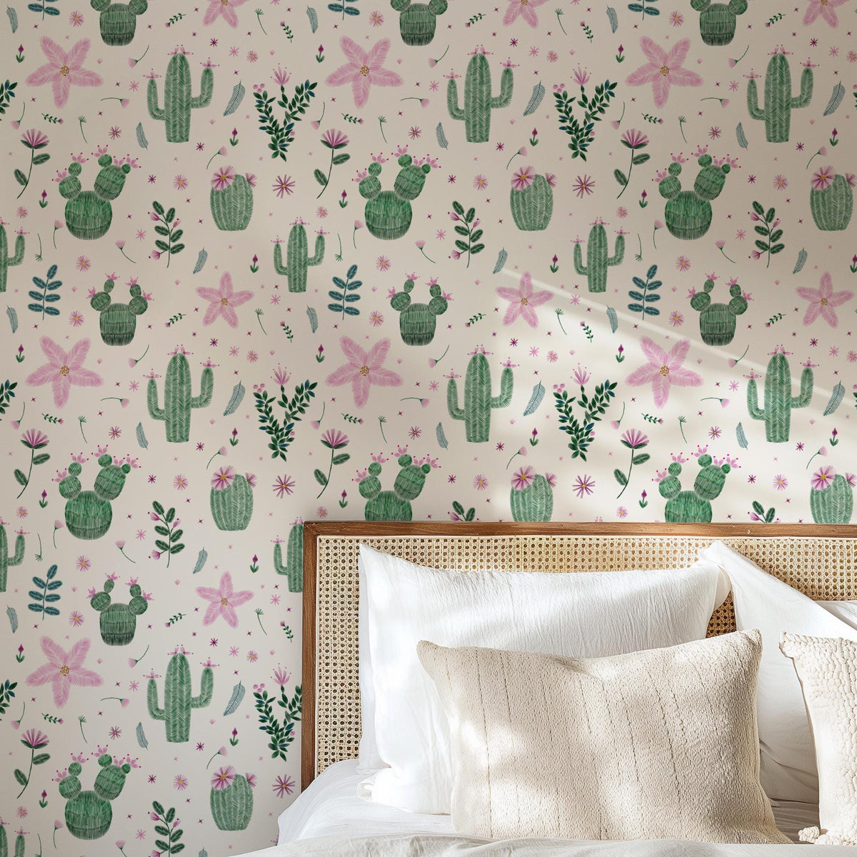 a bedroom with a wallpapered wall adorned with a repeating pattern of cacti and flowers in shades of pink and green. The wallpapered wall is complemented by a wooden headboard and a white bedding set, creating a cozy and inviting atmosphere.